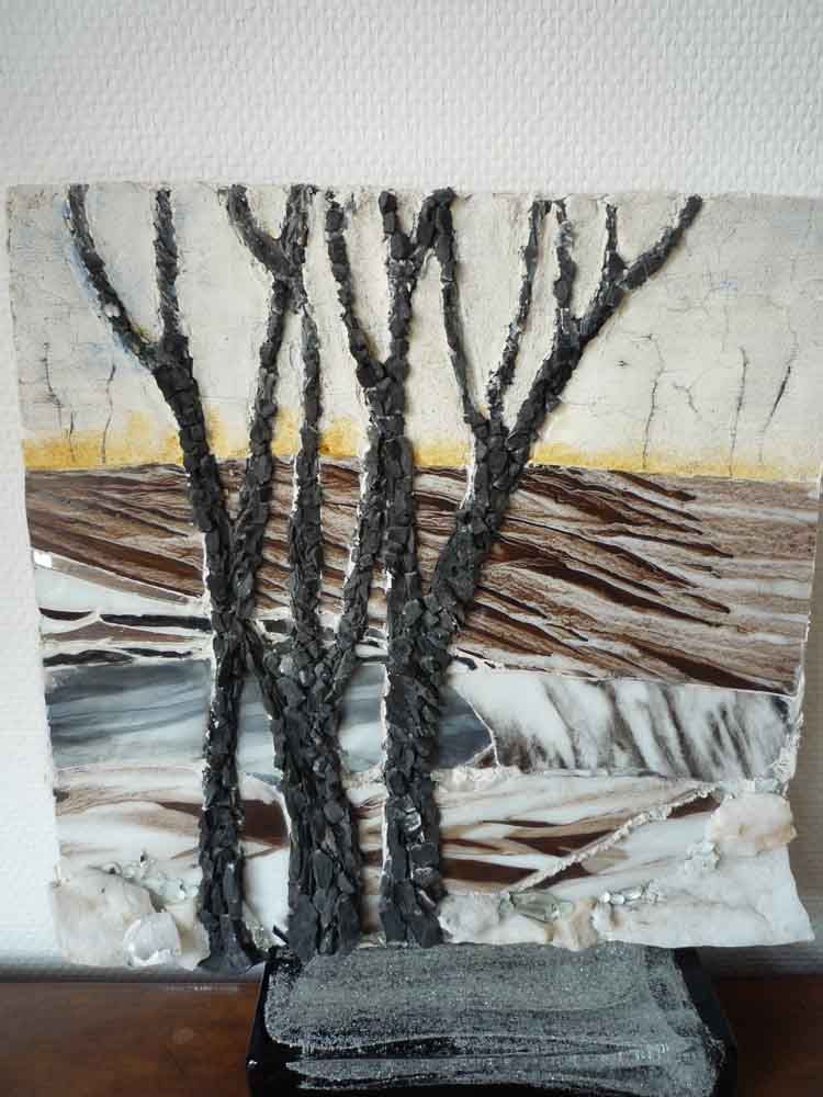 Vitrail représentant des arbres dénudés au coucher du soleil, sur un fond texturé aux tons neutres.