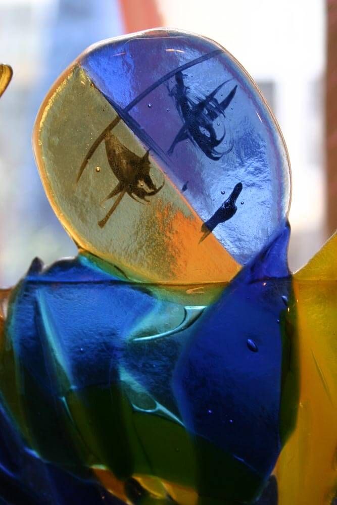 Art en verre, jaune et bleu, avec des formes abstraites incrustées.