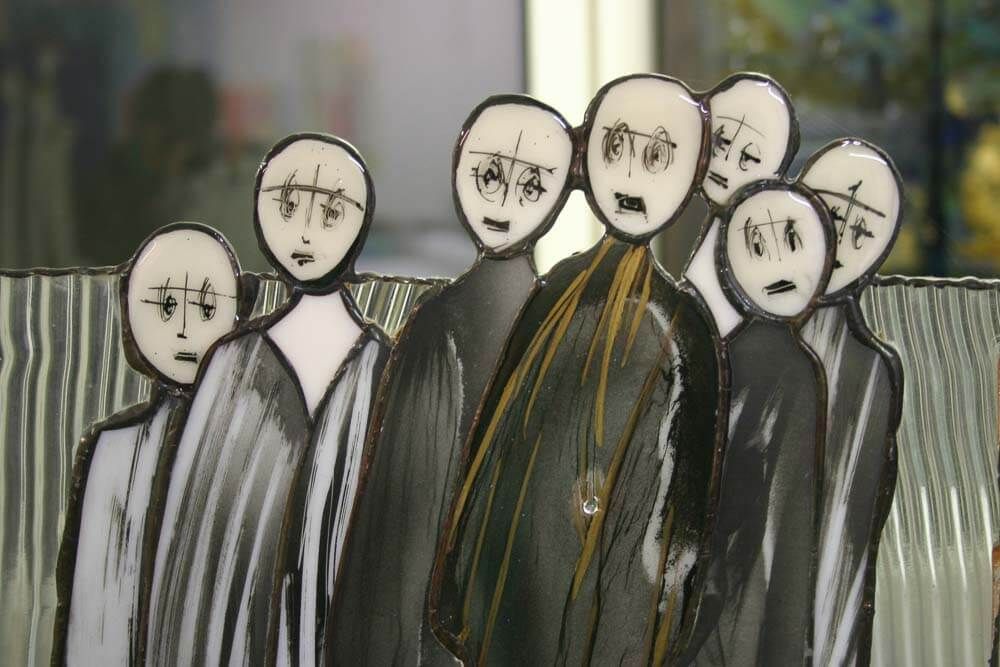 Groupe de silhouettes sans visage, vêtues de capes noires et arborant des expressions de choc, devant un fond flou.