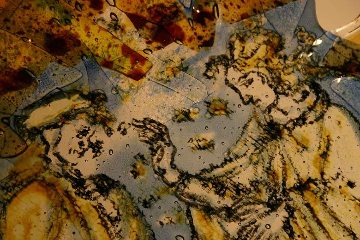 Détail d'un vitrail représentant deux personnages de profil, faisant des gestes, avec un émail bleu, blanc et brun.