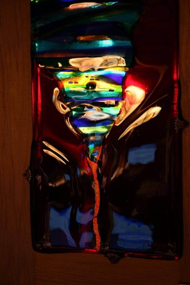 Œuvre d'art abstraite en verre aux volutes de couleurs, notamment bleues, rouges et jaunes, encadrée dans un cadre en bois.