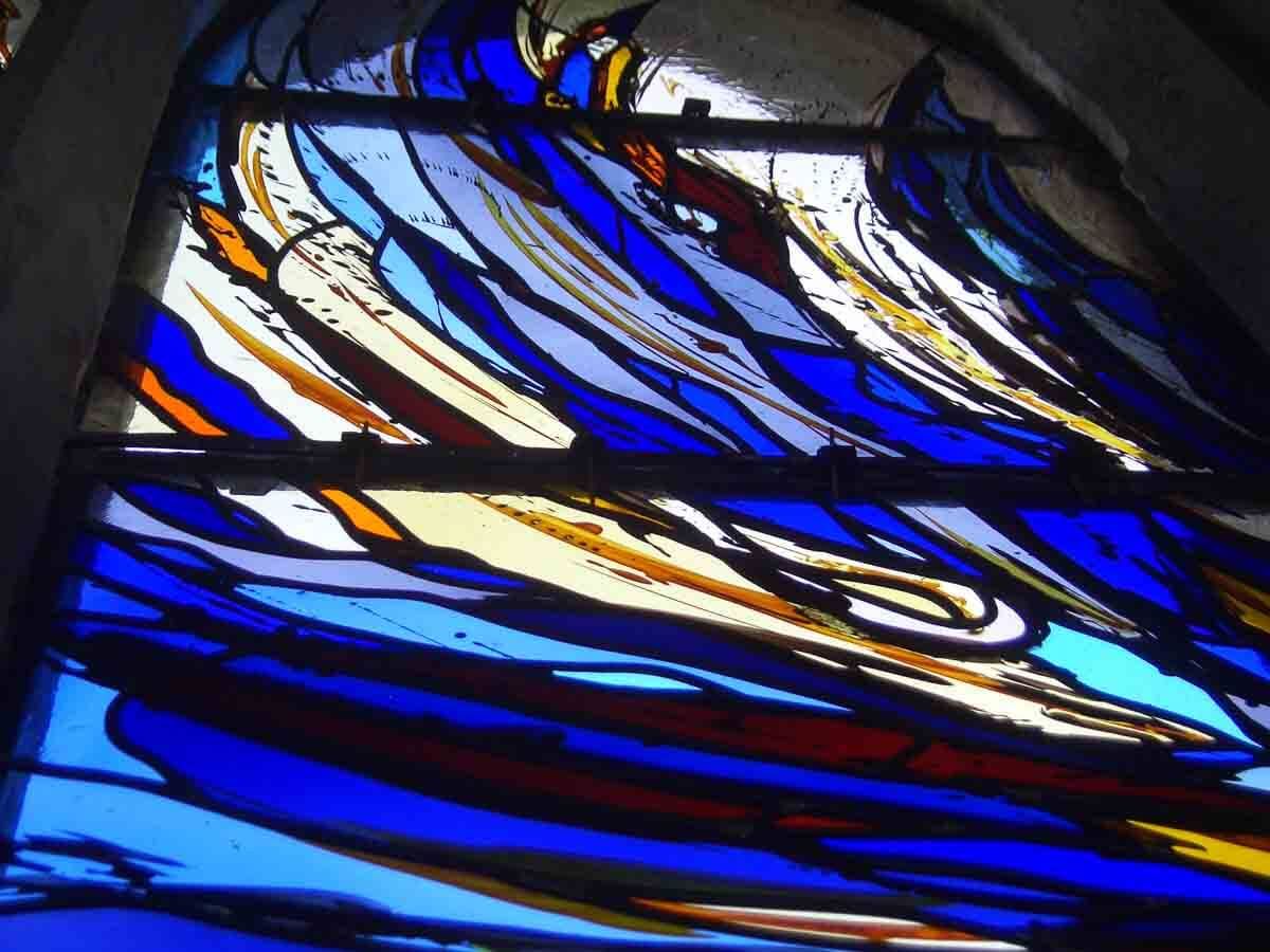 Vitrail orné de motifs abstraits tourbillonnants bleus, blancs et bruns.