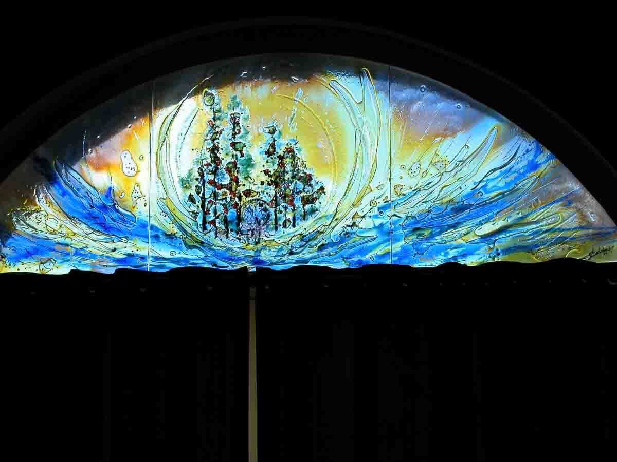 Vitrail en arc représentant une ville au milieu de vagues bleues et d'un ciel jaune.