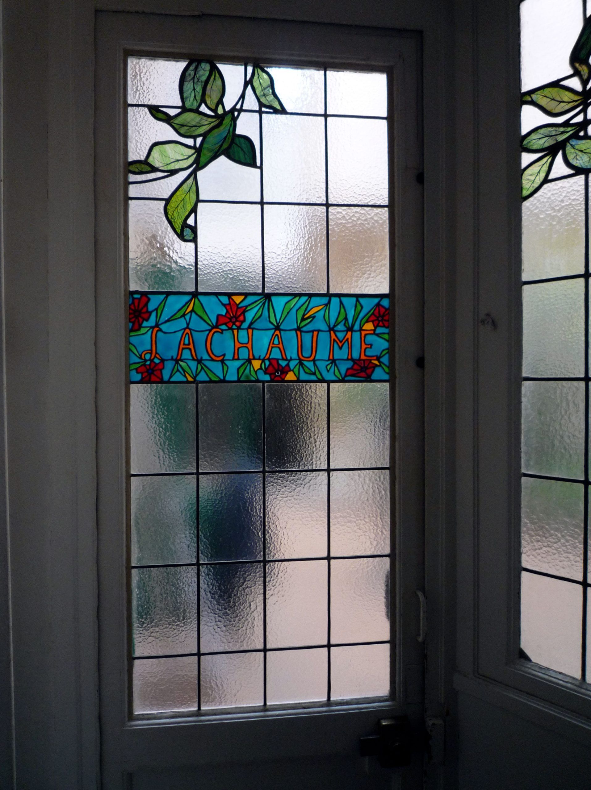 Vitrail à motifs de feuilles, bannière turquoise portant l'inscription « RÉUSSITE ». Verre dépoli quadrillé.