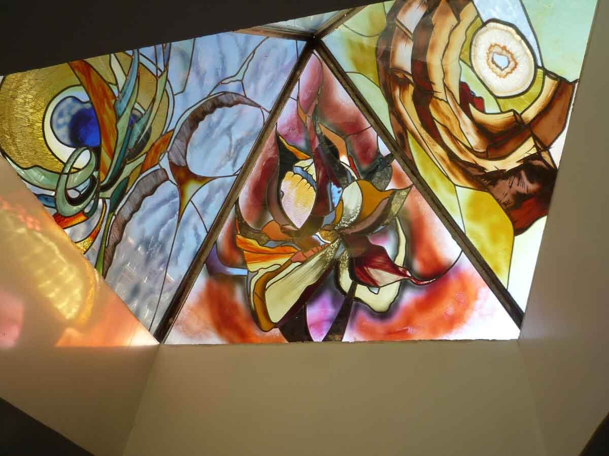 Puits de lumière en vitrail aux motifs abstraits et aux couleurs chaudes.