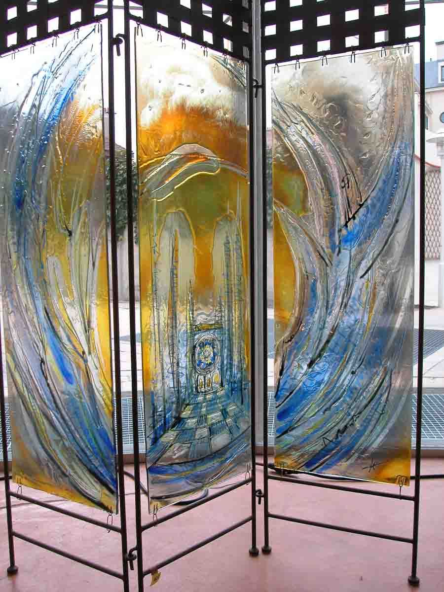 Paravent à trois panneaux orné d'un motif abstrait et fluide en vitrail bleu, jaune et orange.