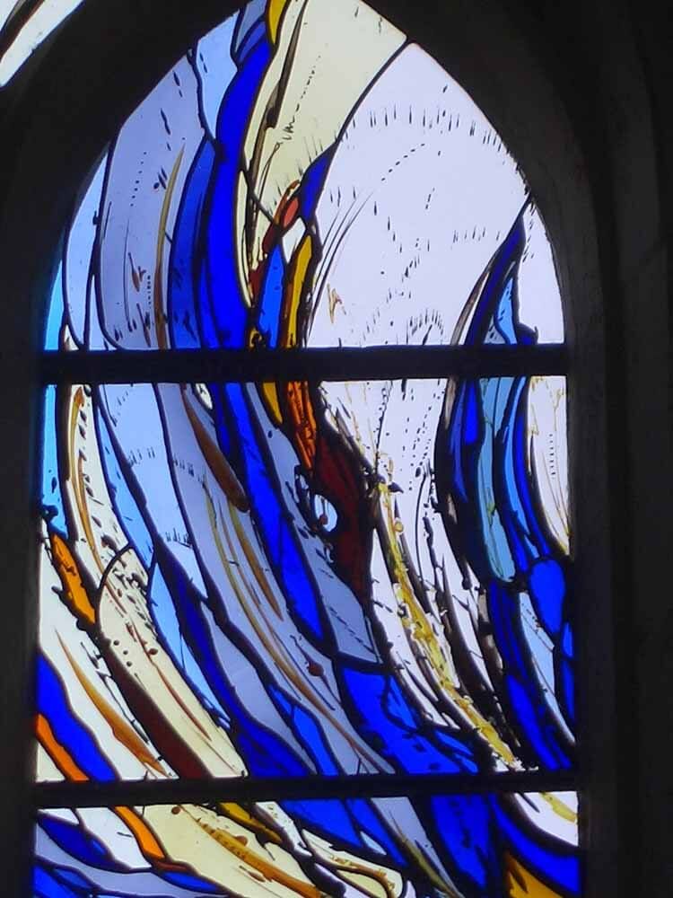 Vitrail à motif abstrait bleu, blanc, jaune et orange.
