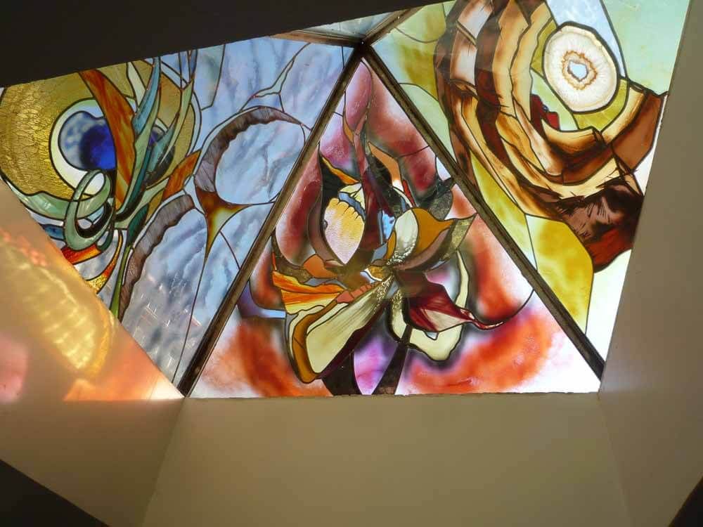 Puits de lumière en vitrail aux motifs abstraits et aux couleurs chaudes.