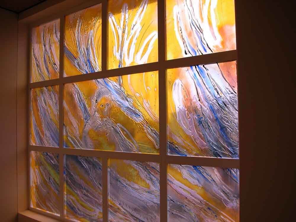 Vitrail orné de motifs abstraits fluides jaunes, bleus et blancs.