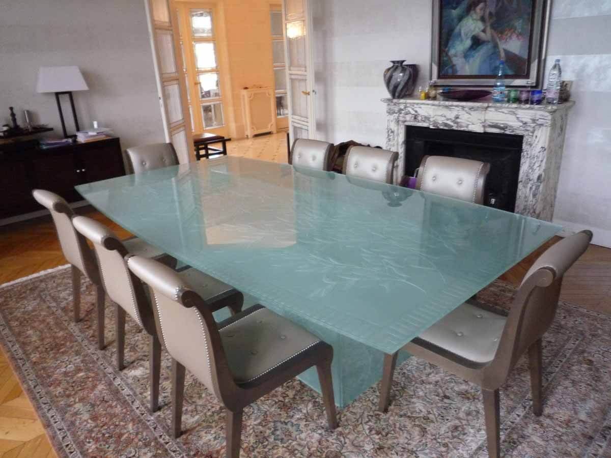 Salle à manger avec une longue table en verre, huit chaises et une cheminée.