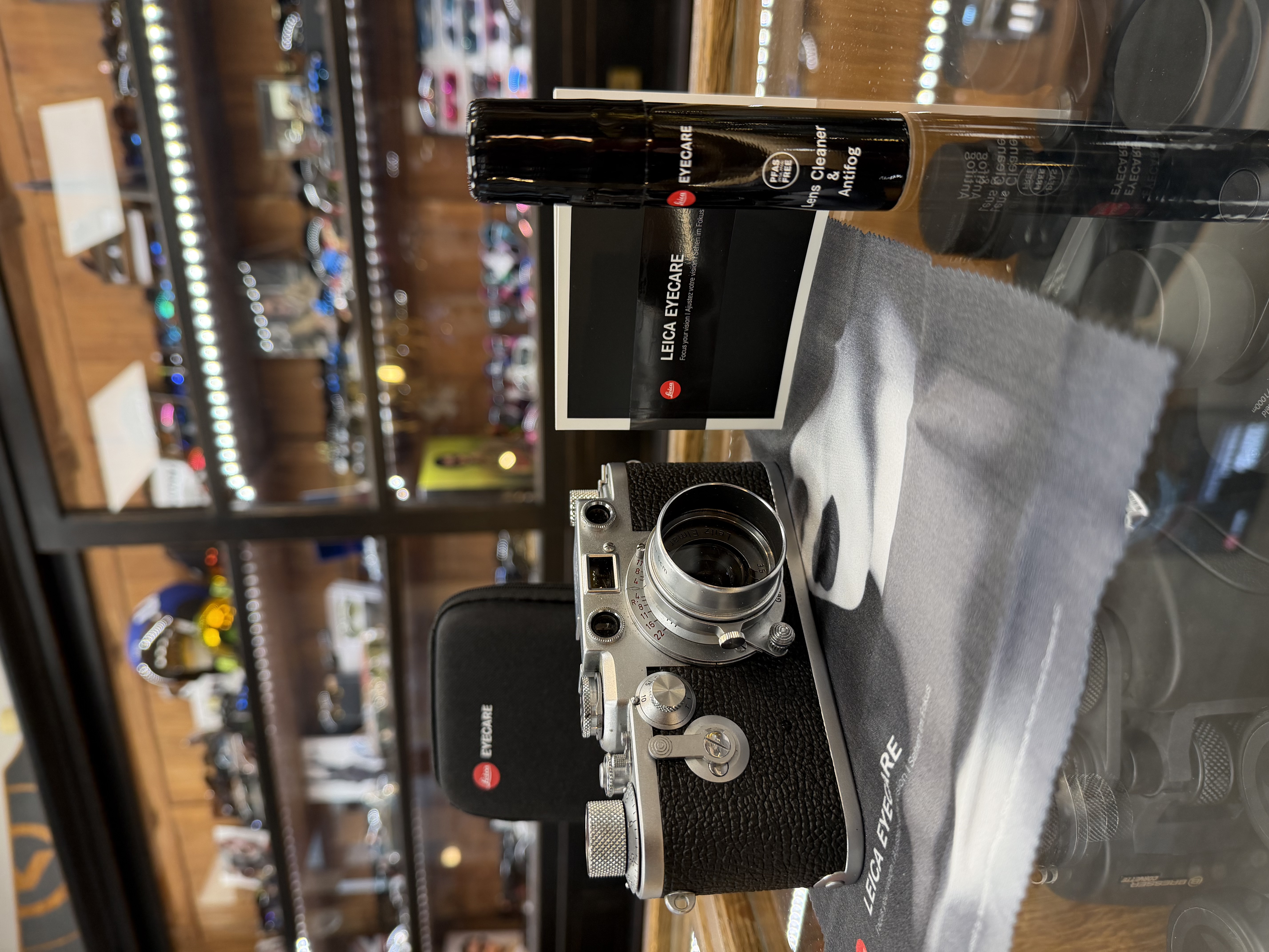 Un optométriste tenant des lunettes, avec un tableau optométrique en arrière-plan.