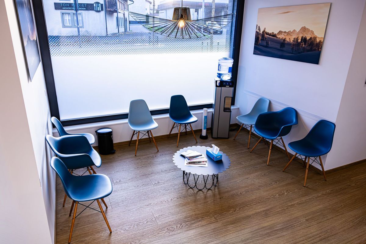 Salle d'attente du cabinet du Dr Lekeufack, avec des chaises bleues et une table contenant des magazines.