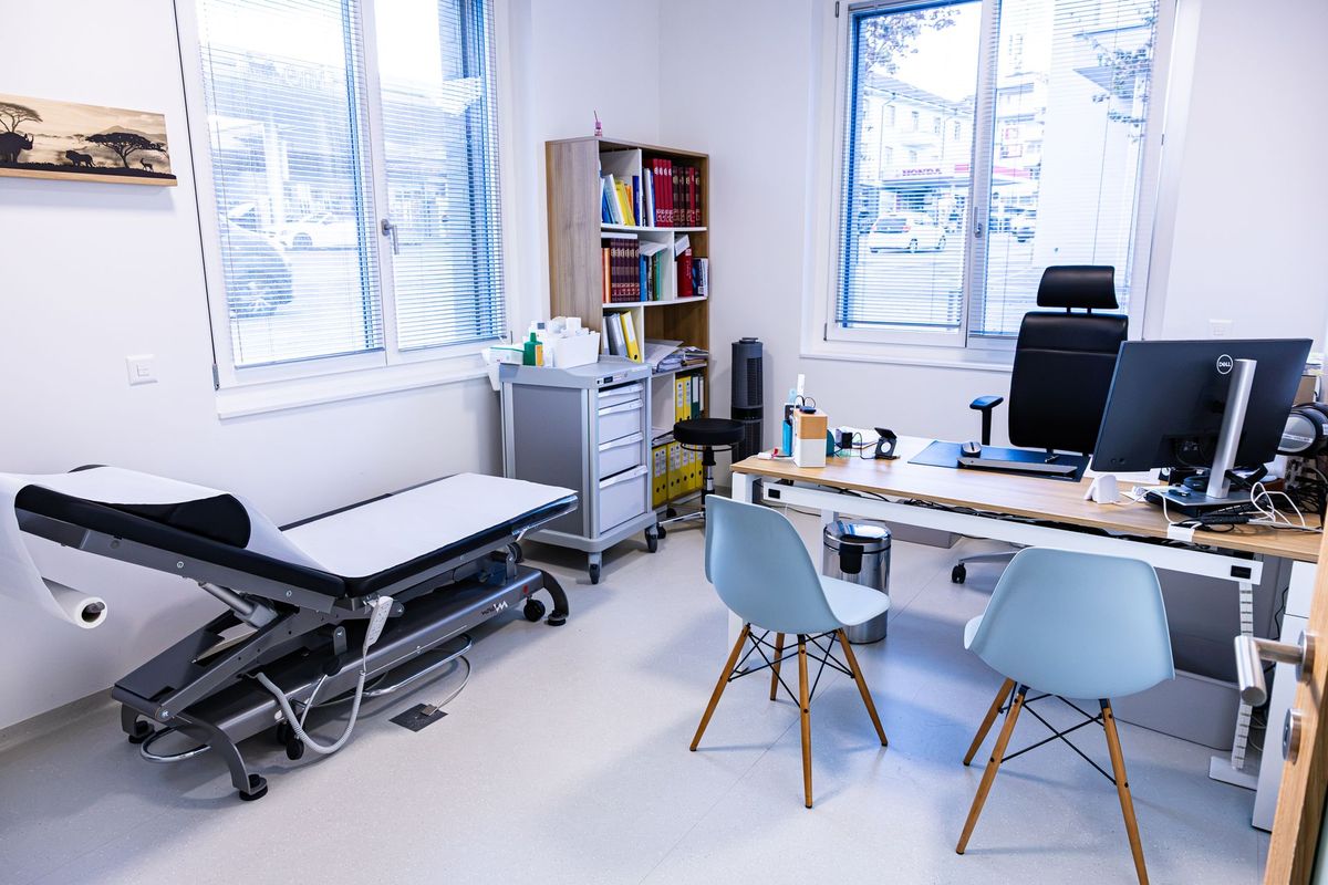 Salle de consultation du cabinet du Dr Lekeufack, comprenant le bureau du docteur ainsi qu'une table de travail.
