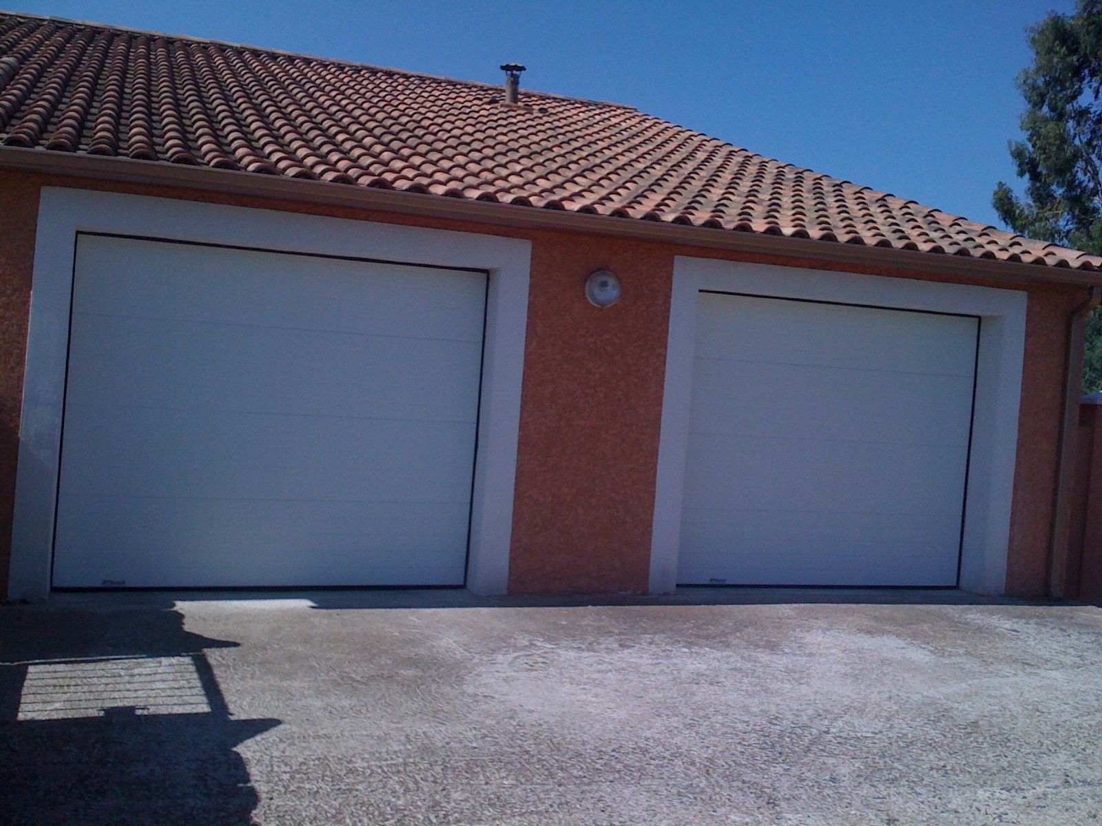 Deux portes de garages sectionnelles blanches et murs rouges