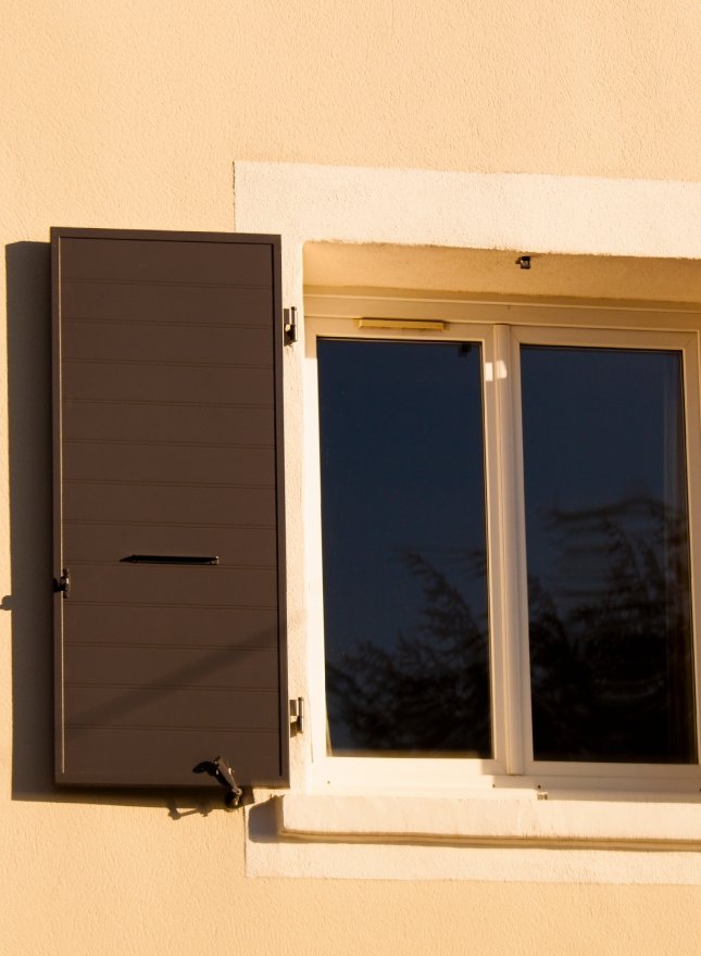 Volet marron sur mur en crépis crème