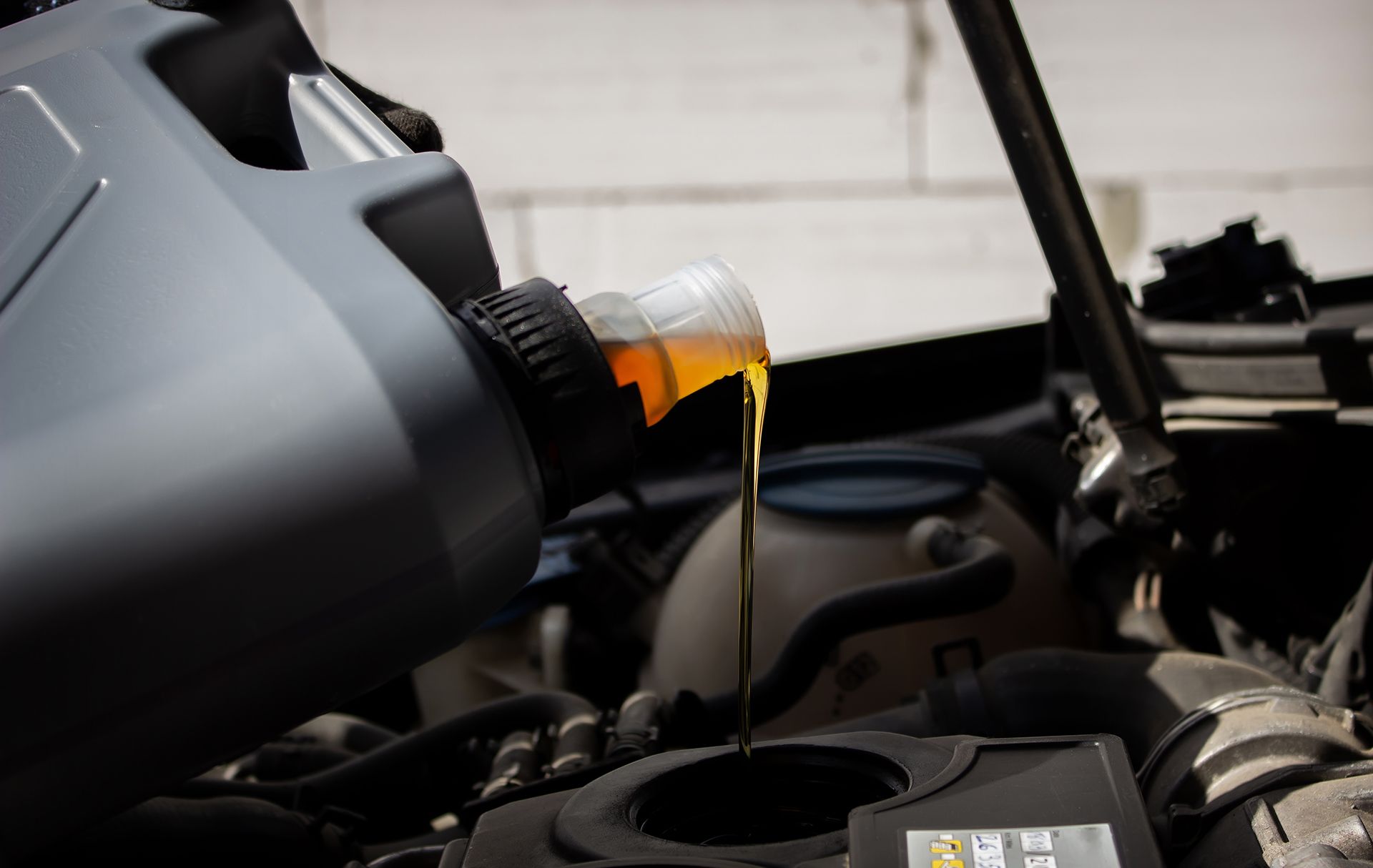 Ao despejar óleo no motor de um carro, o líquido fica amarelo, deixando visíveis componentes pretos e metálicos.