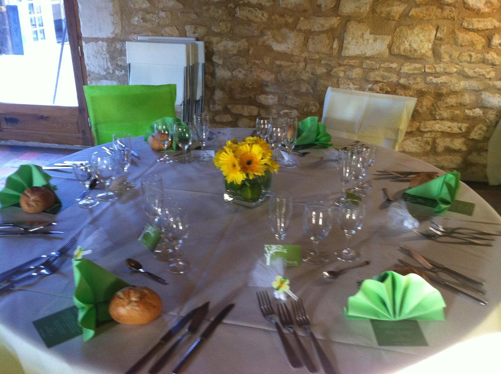 Table de réception avec serviettes vertes et fleurs jaunes.