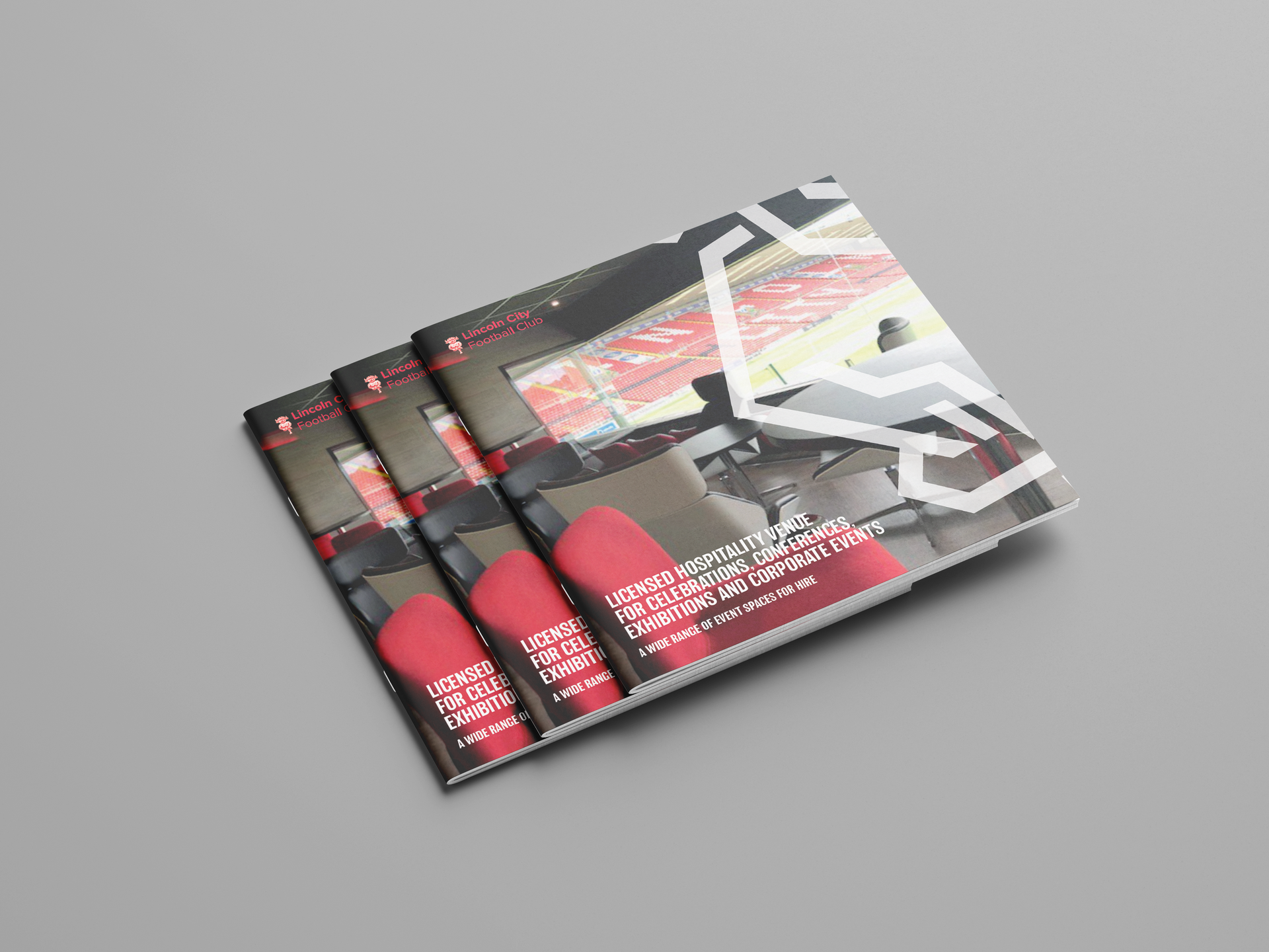 Three identical booklets stacked diagonally, featuring a dark, abstract cover design with a prominent red graphic element.