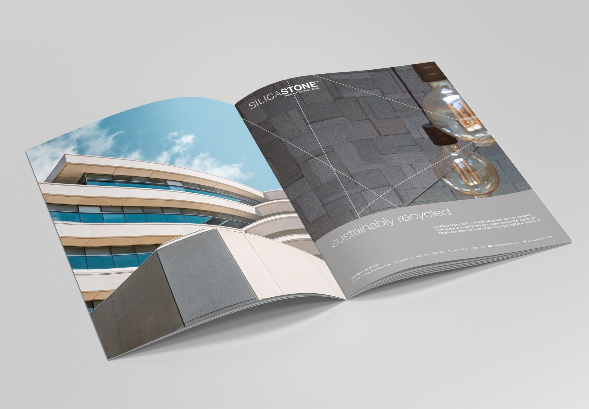 An open brochure shows a modern building on the left and a stone wall with hanging light bulbs on the right.