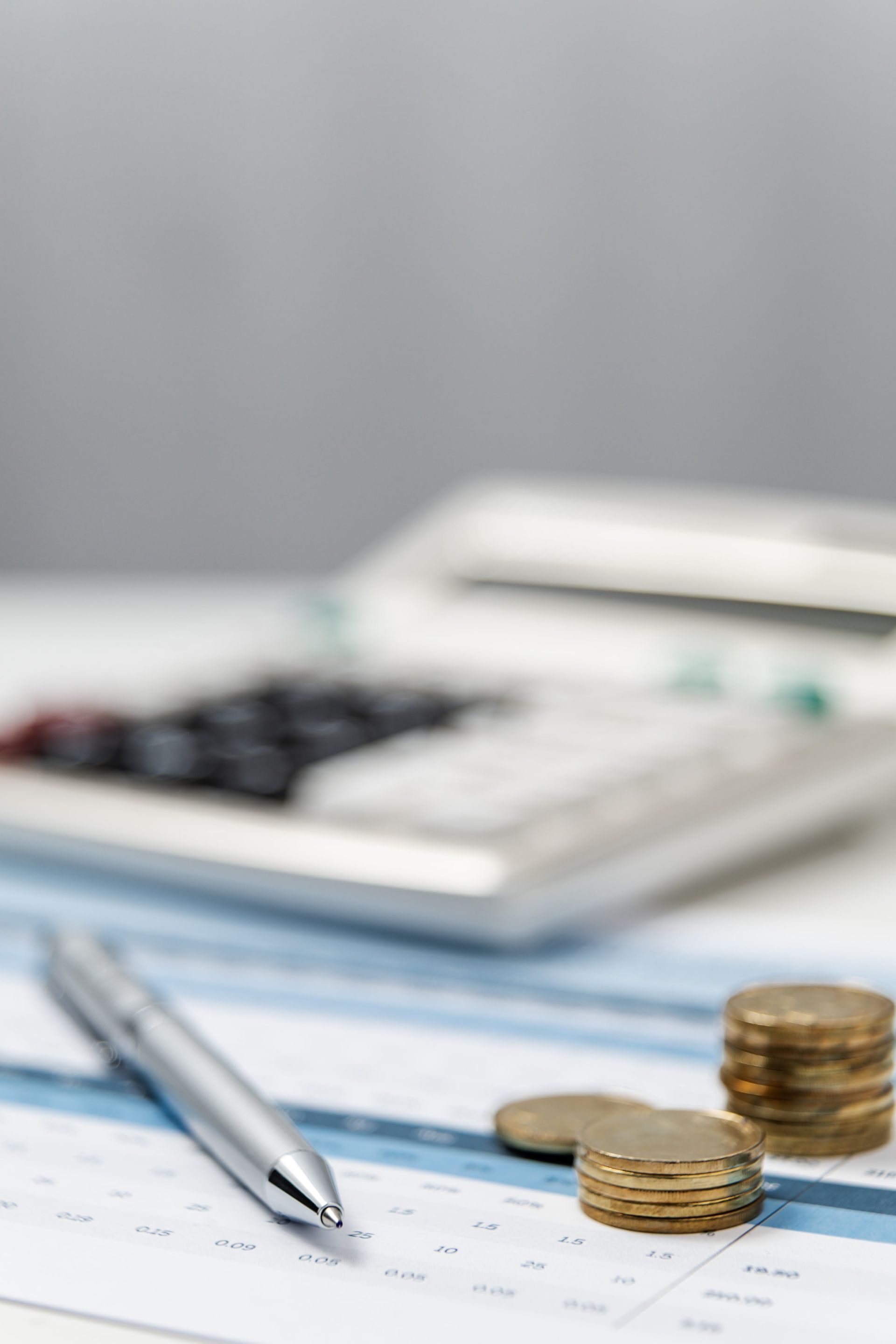 Münzen, Kugelschreiber und Taschenrechner liegen auf Dokumenten