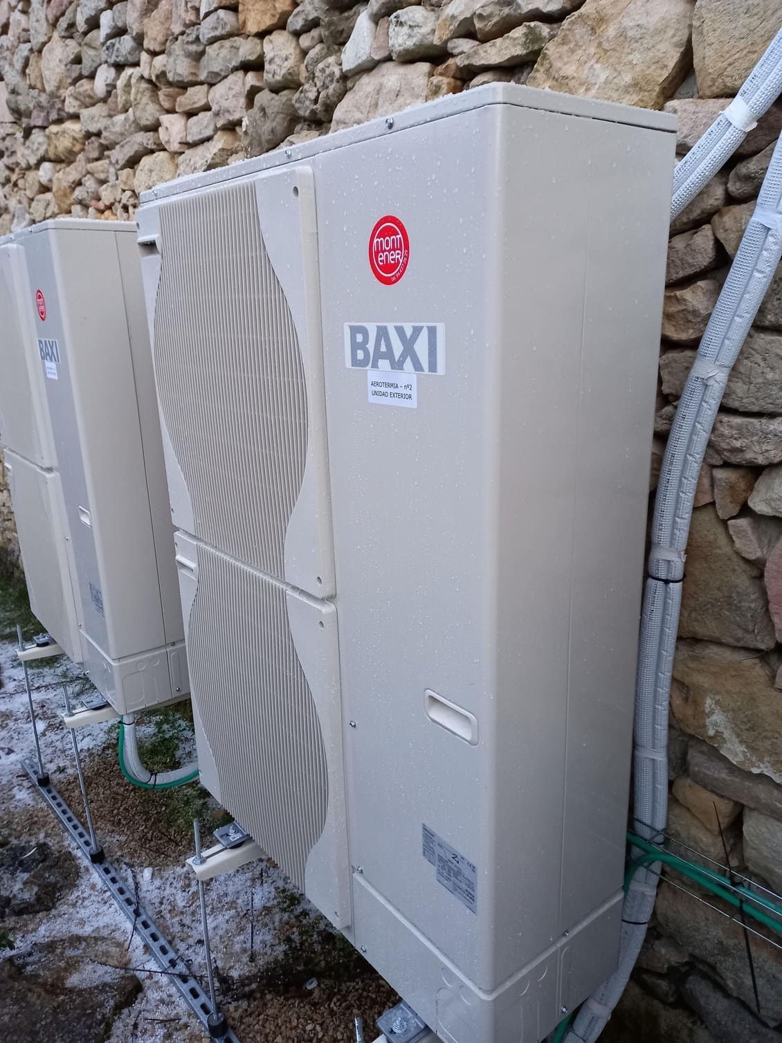 Una fila de aparatos de aire acondicionado están colocados uno al lado del otro frente a una pared de piedra.