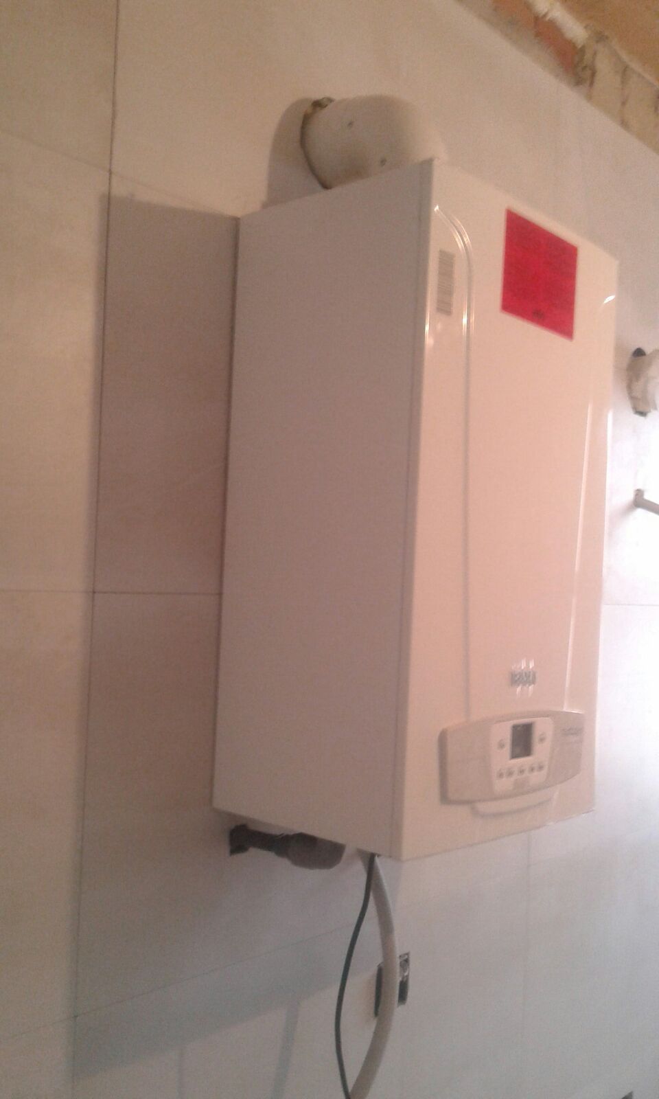 Una caldera blanca está colgada en una pared blanca.