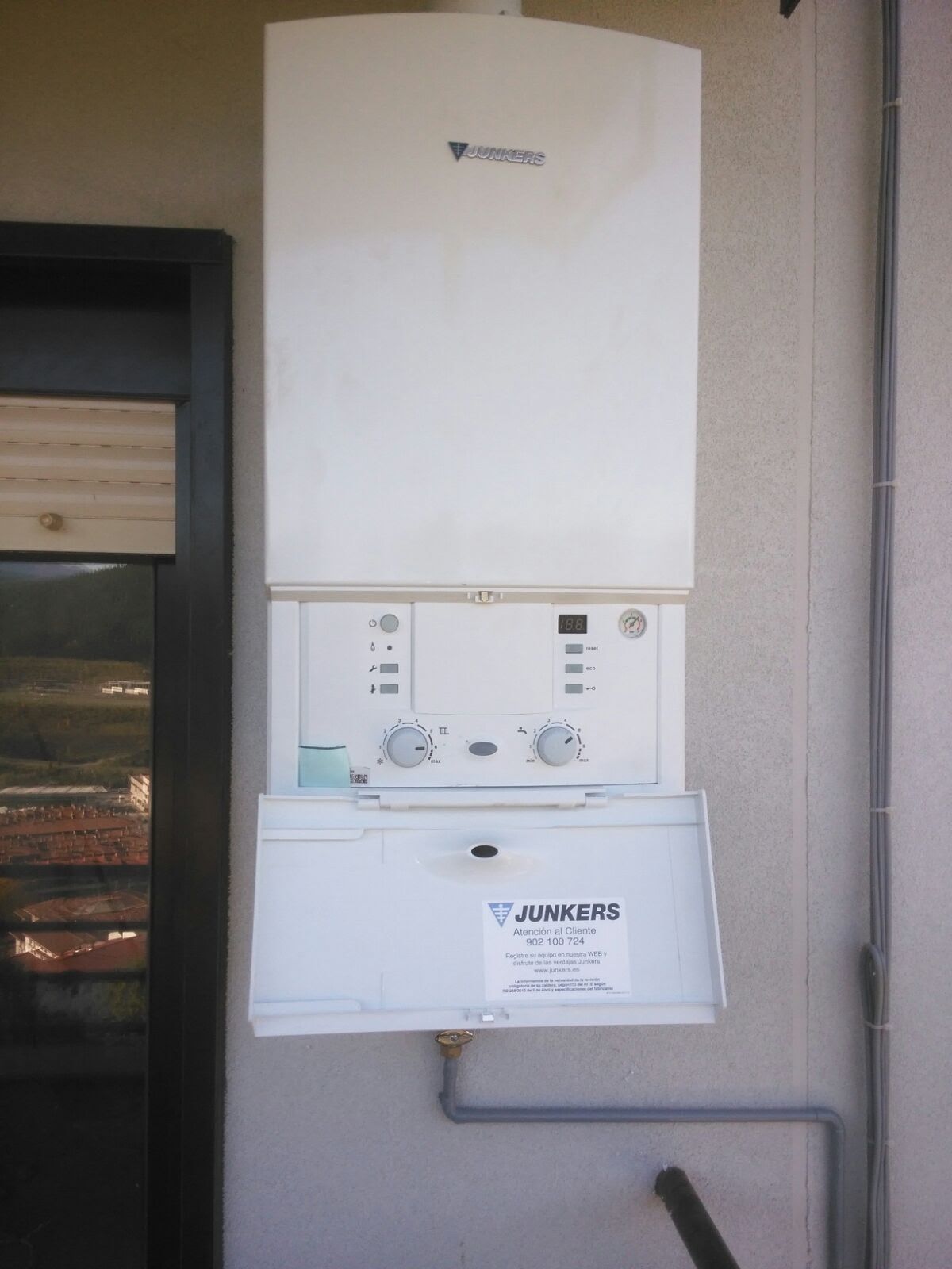 Una caldera Junkers blanca está colgada en una pared.