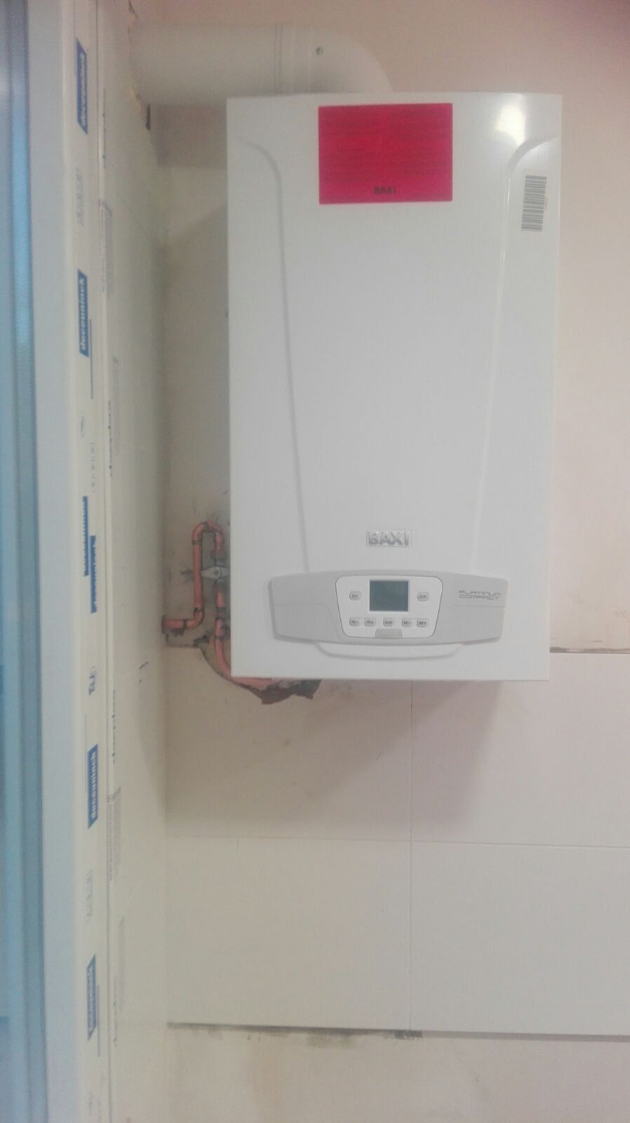 Una caldera blanca está colgada en una pared blanca.