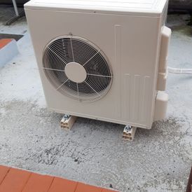 Un gran ventilador blanco se encuentra sobre una superficie de hormigón.