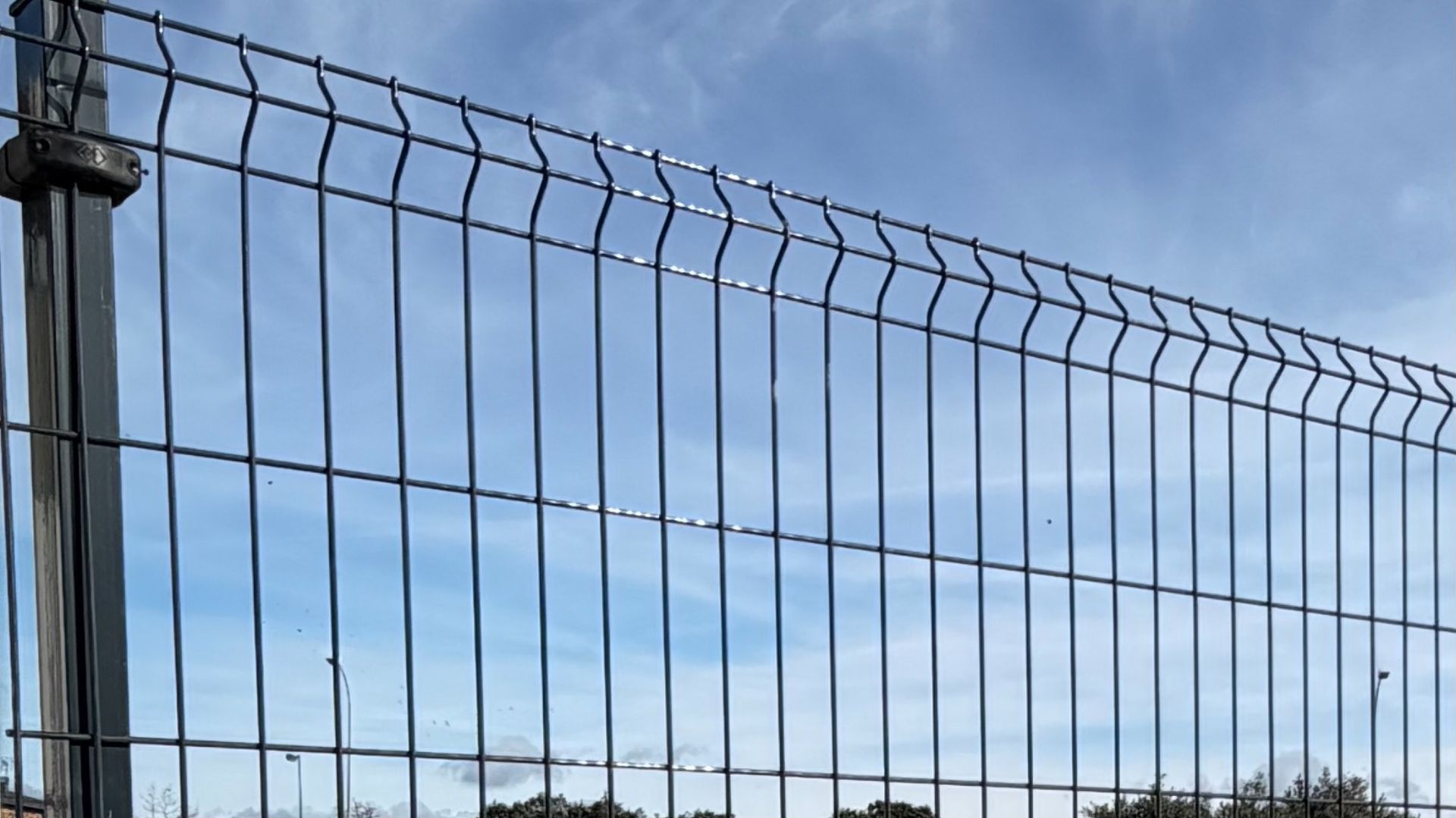 Valla de malla metálica contra un cielo azul.