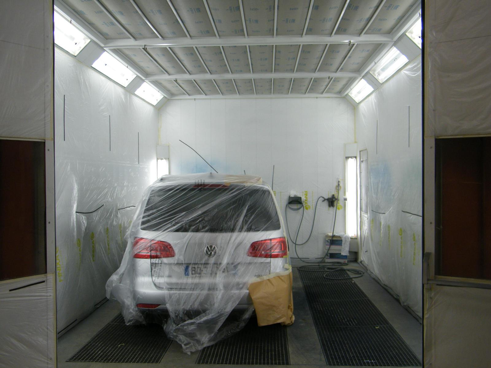 Vue de derrière d'une voiture allemande grise avec protection sur la carrosserie en cours de travaux de peinture.