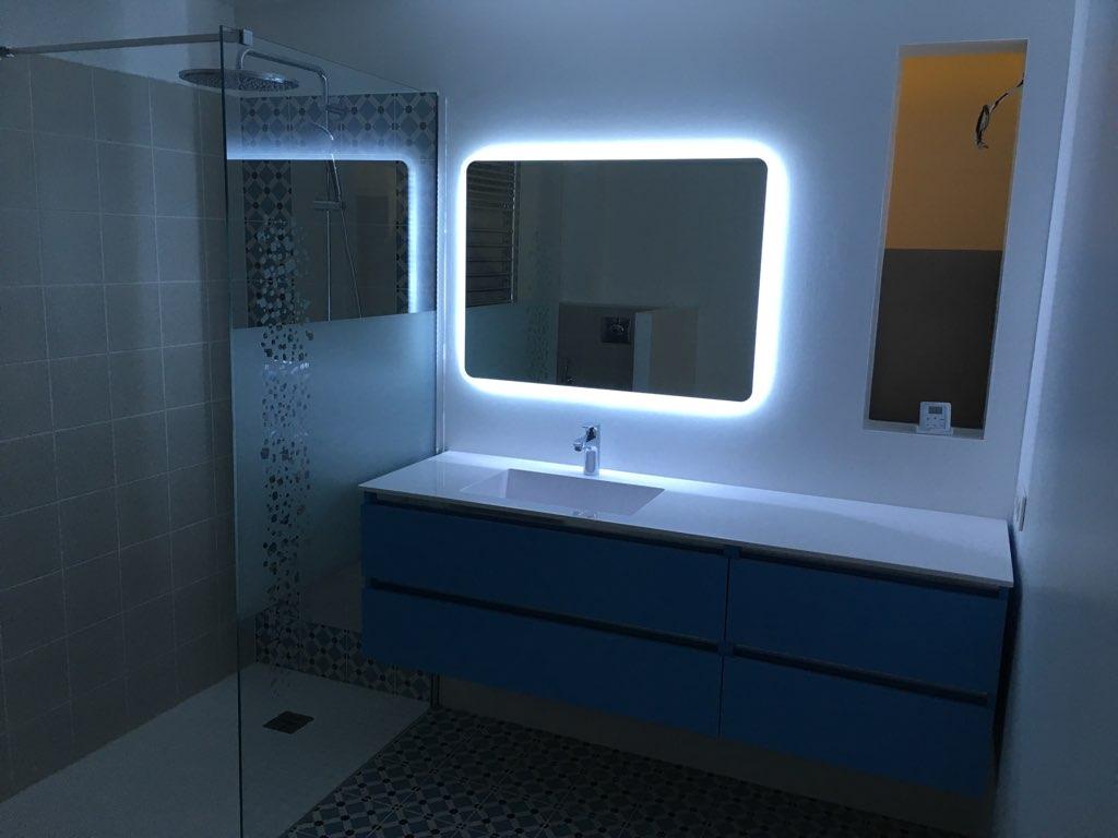 Rénovation de salle de bains terminée avec placement d'un miroir à néon bleu pour un style contemporain