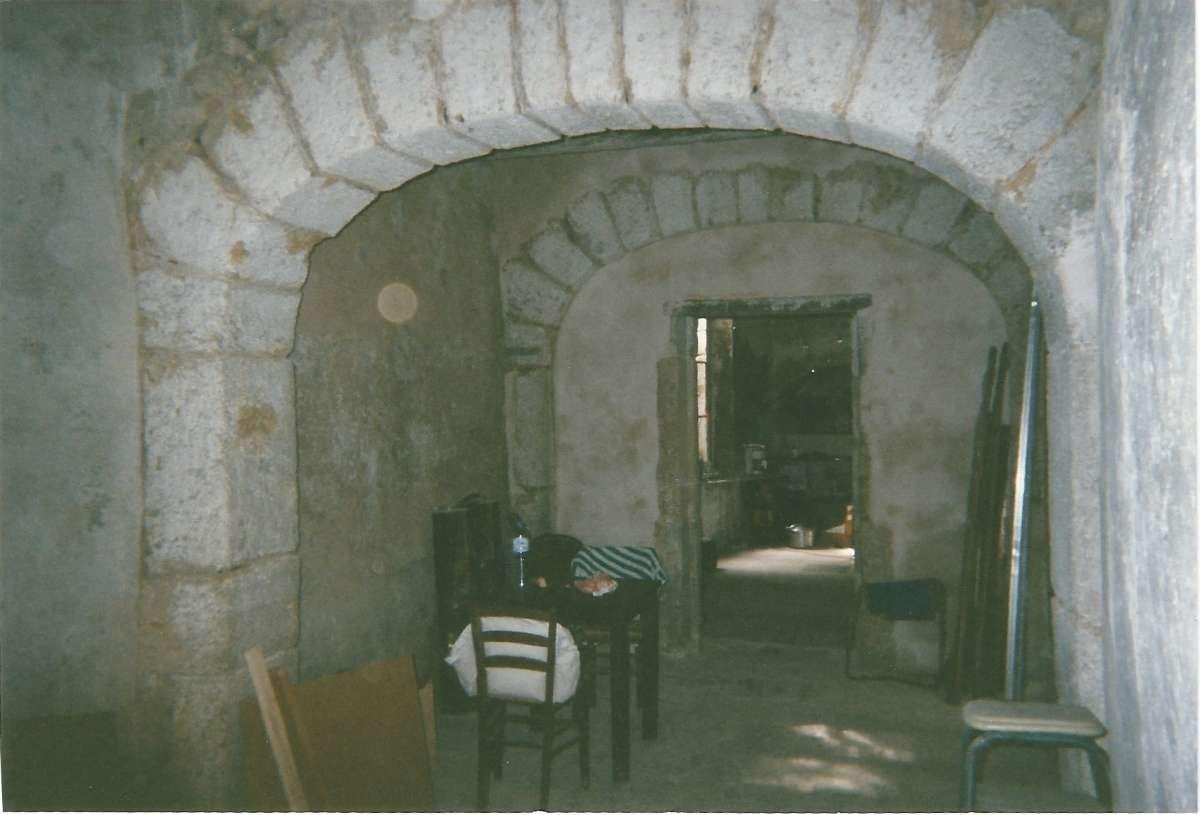État d'un intérieur de bâtiment en pierre avant rénovation avec murs détériorés, sol sans revêtement, éclairage insuffisant...