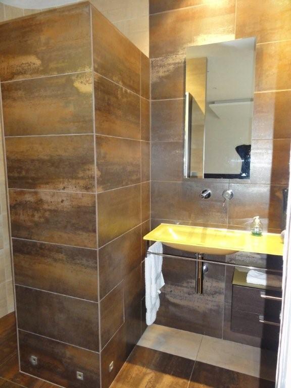 Salle de bains rénovée avec revêtement mural imitation bois et lavabo changé