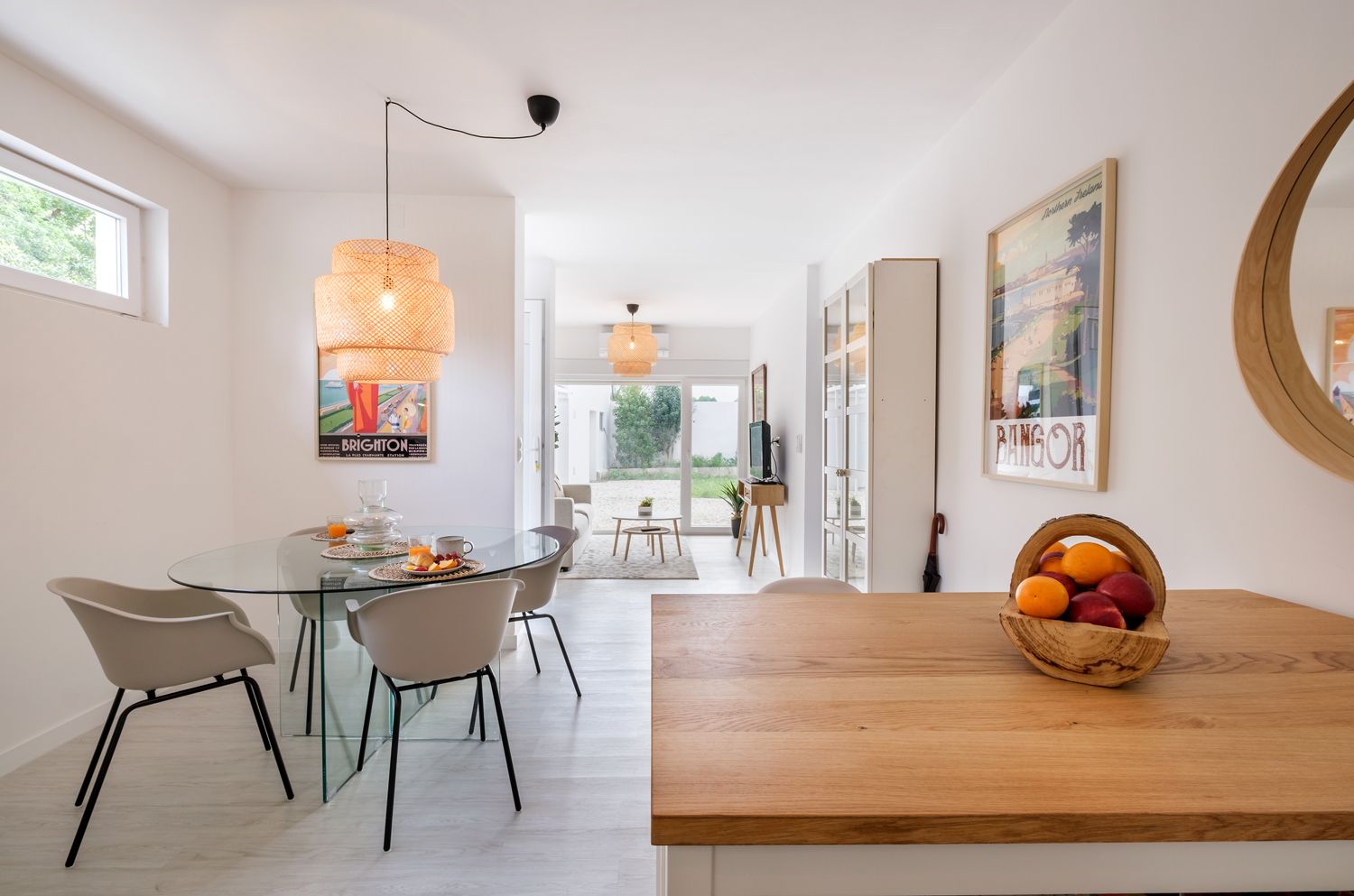 A dining room with a table and chairs and a bowl of fruit on the table.