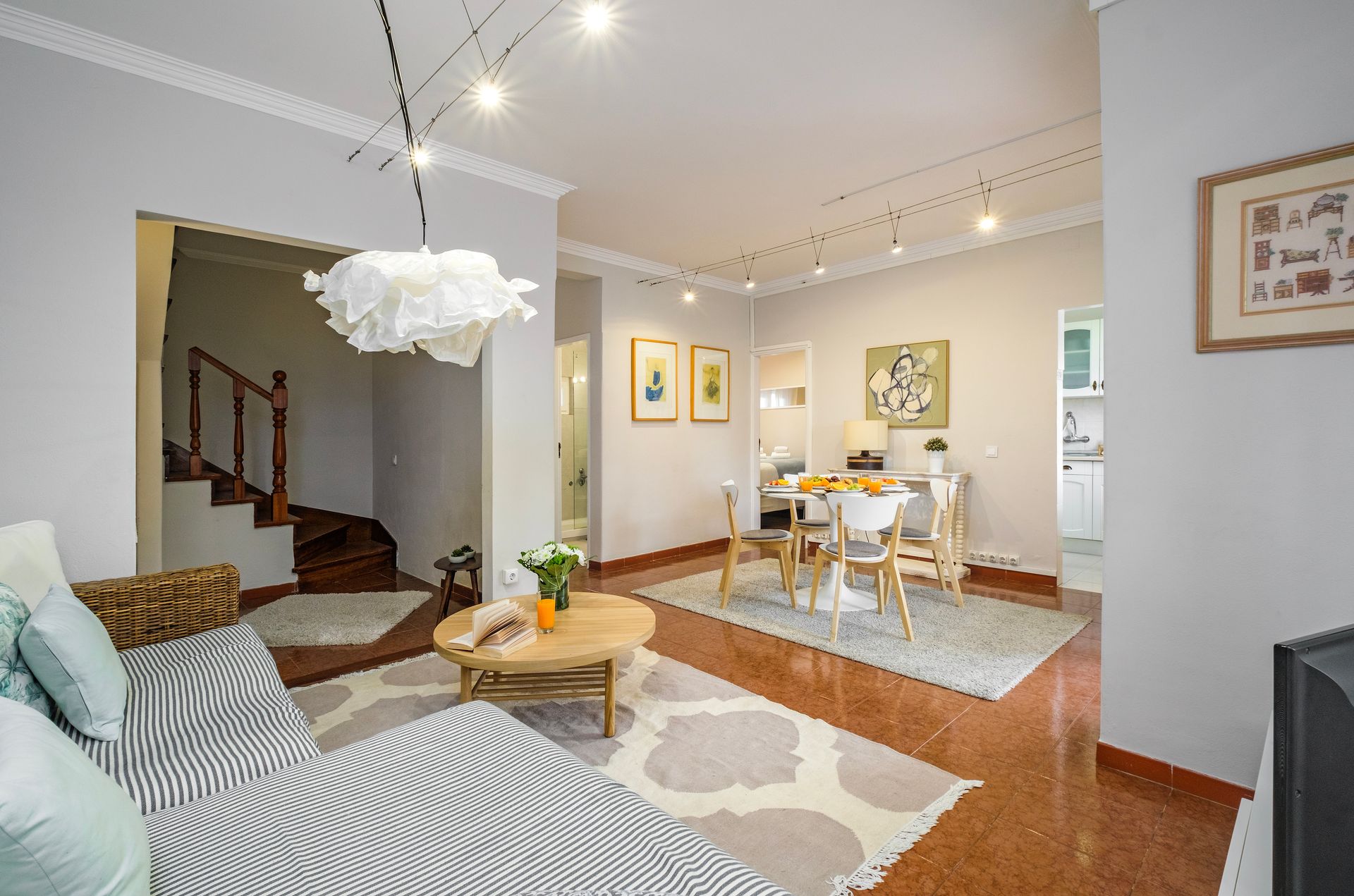 A living room with a couch , table , chairs and stairs.