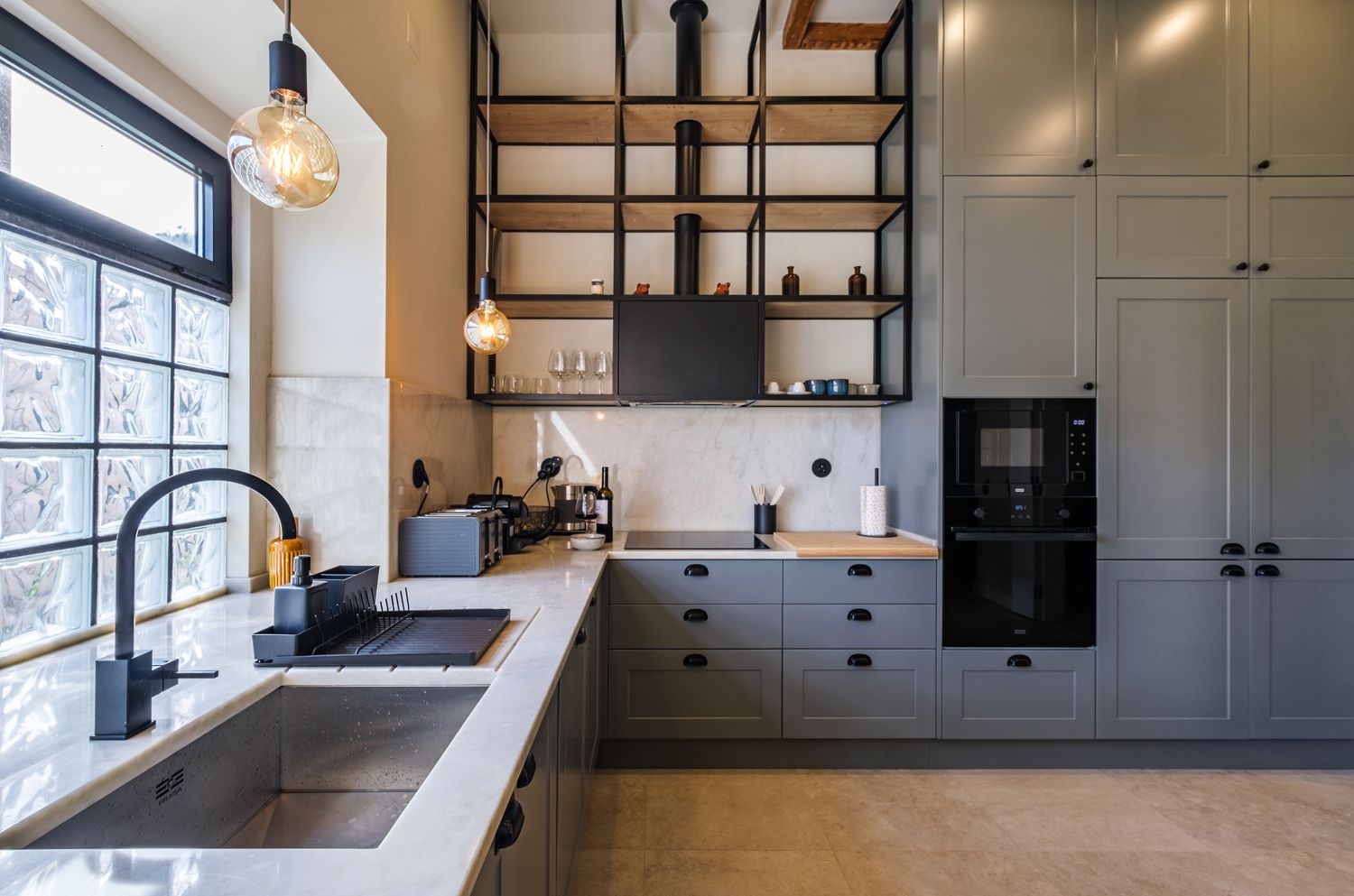 A kitchen with gray cabinets , a sink , and a window.