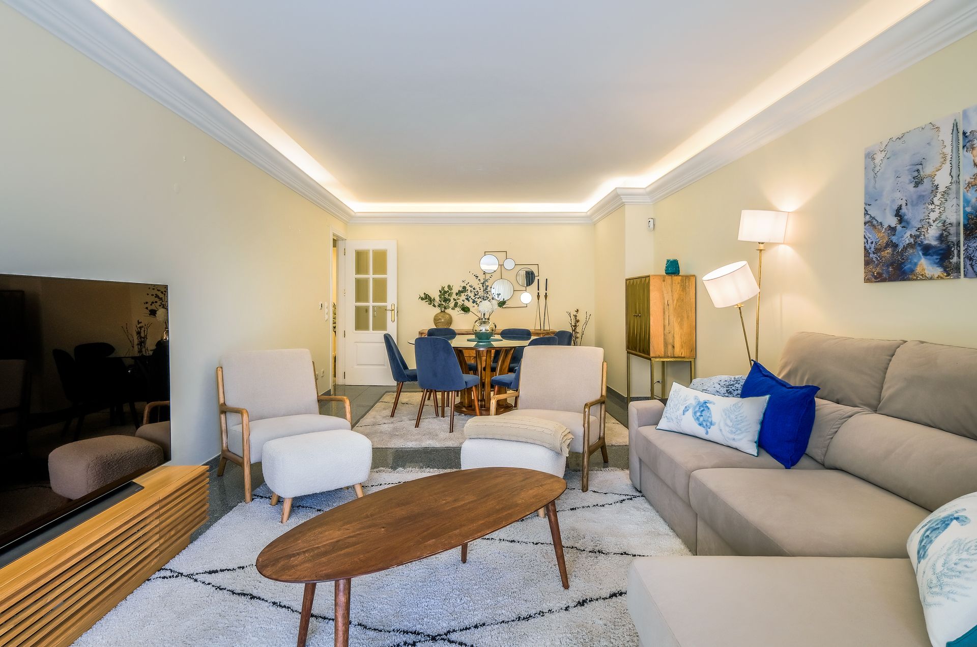 A living room with a couch , chairs , a coffee table and a television.