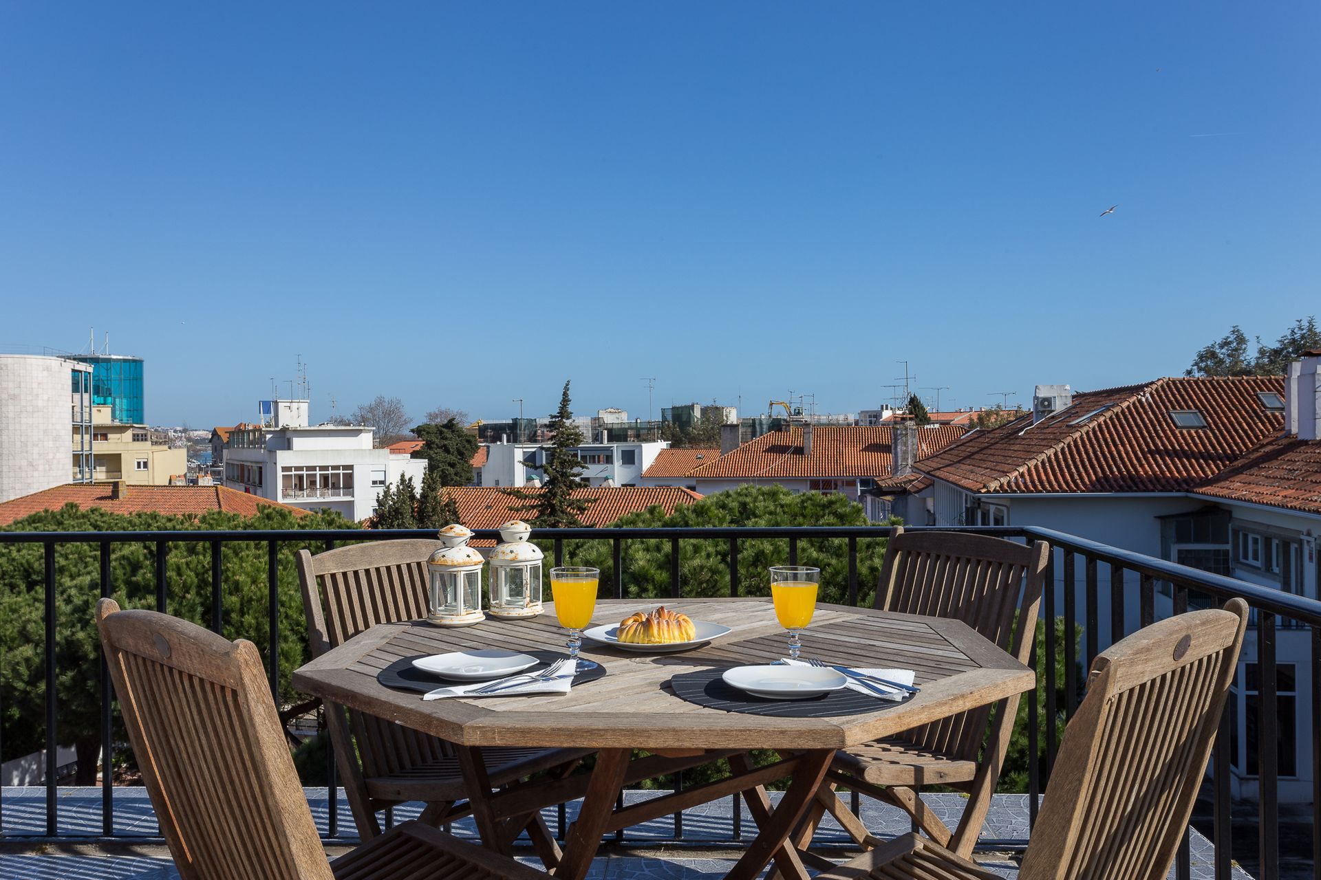 A table and chairs on a balcony with a view of the city.