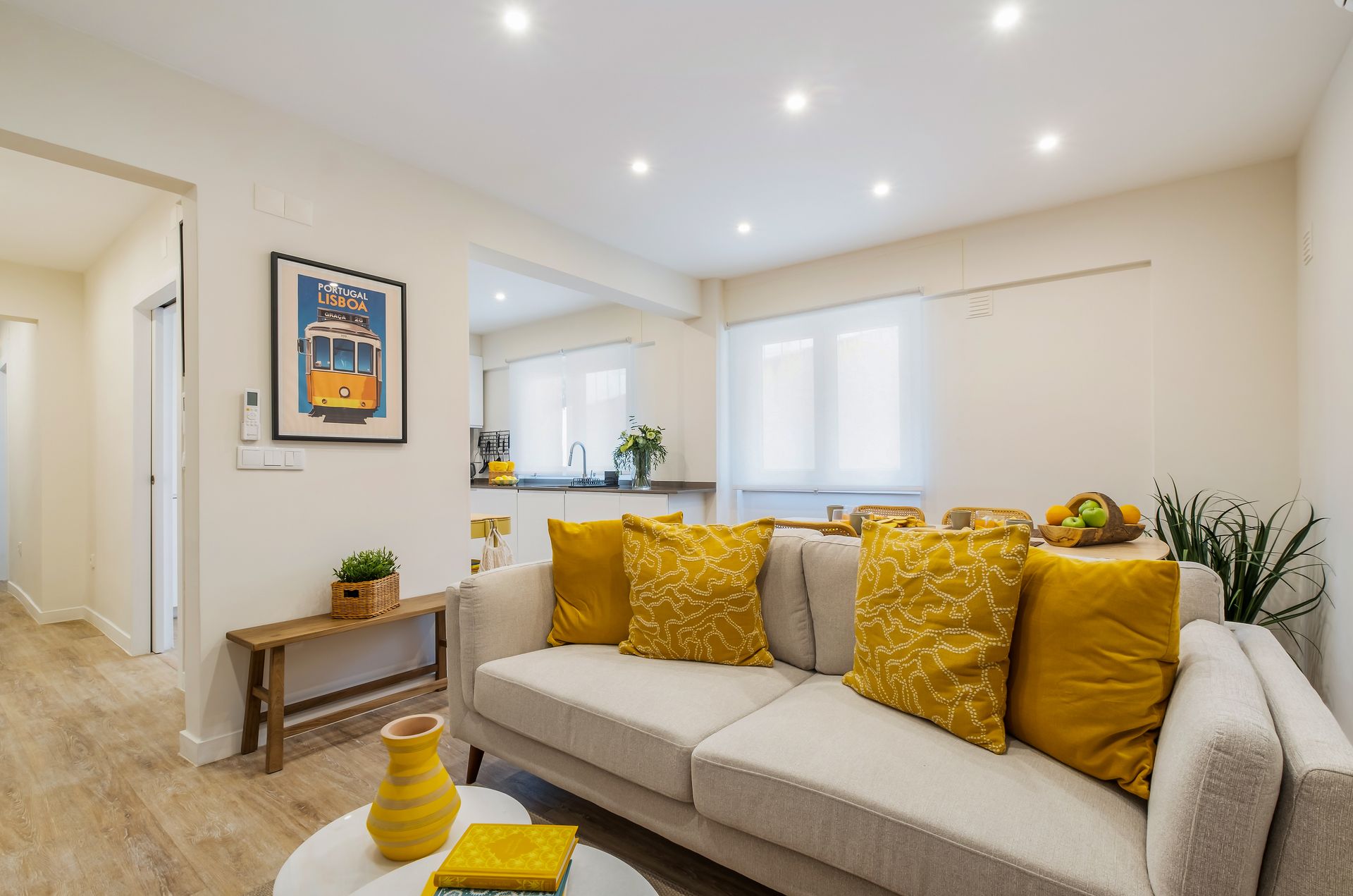 A living room with a white couch and yellow pillows.