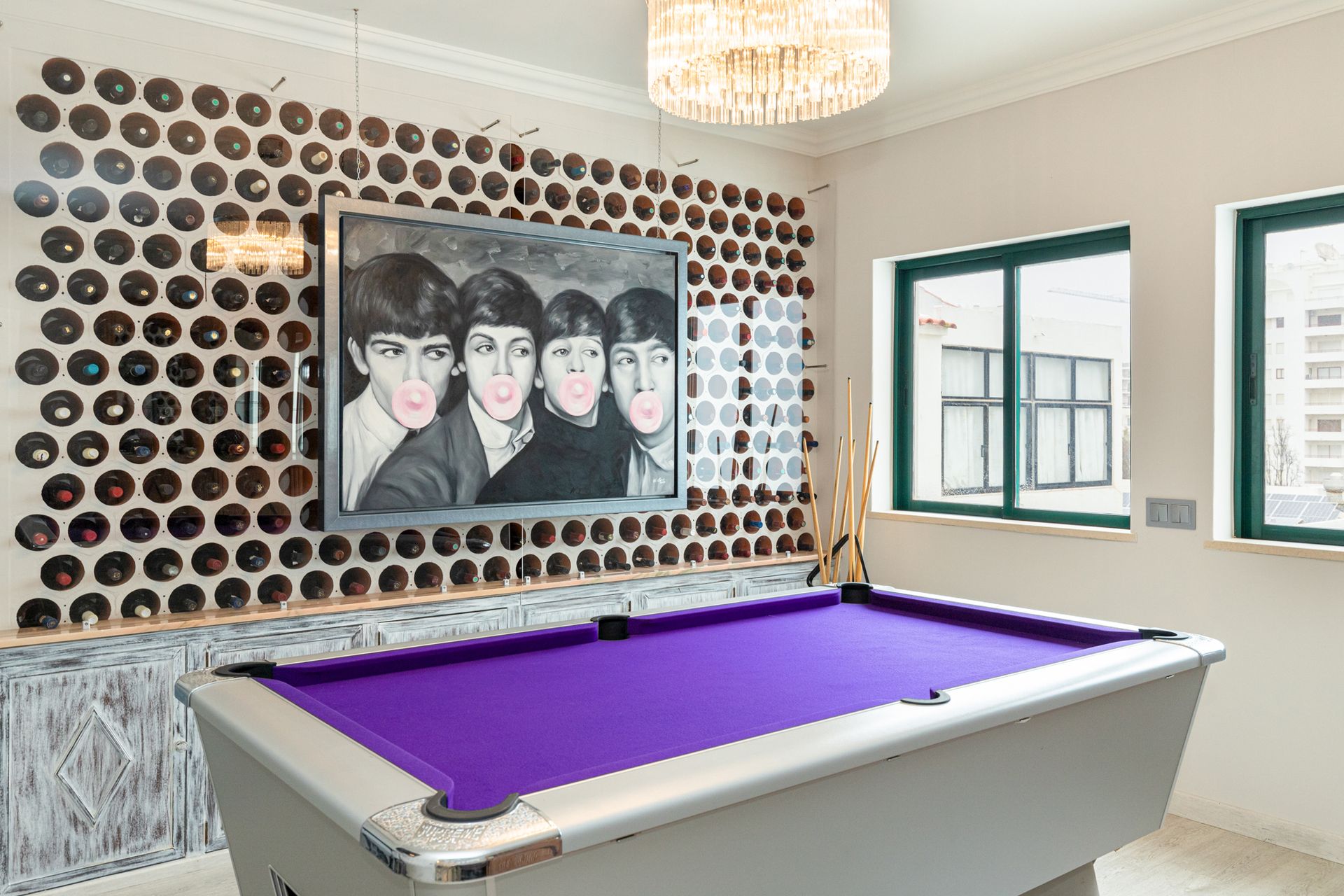 A pool table in a room with a painting of the beatles on the wall.