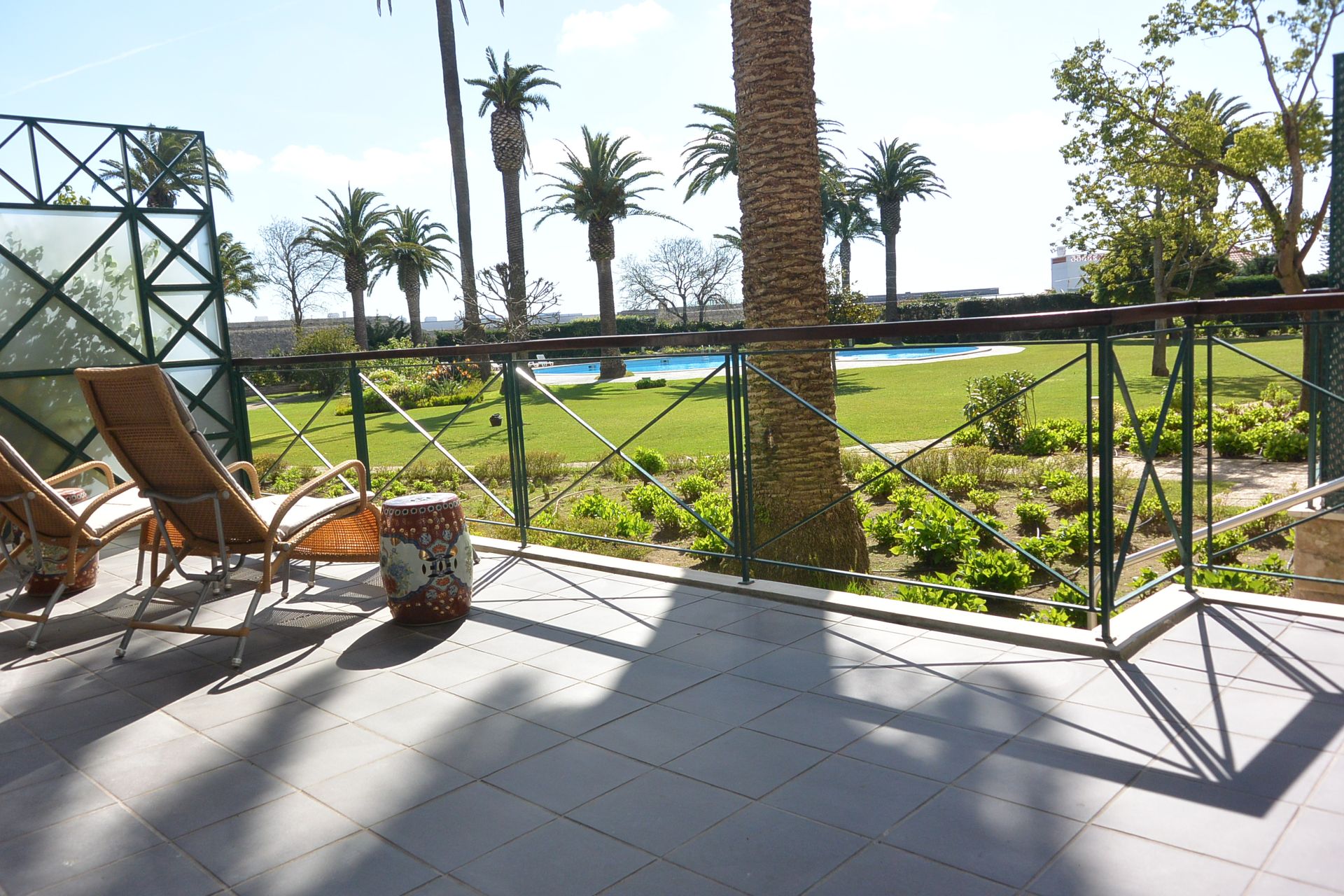 A balcony with a view of palm trees and a pool