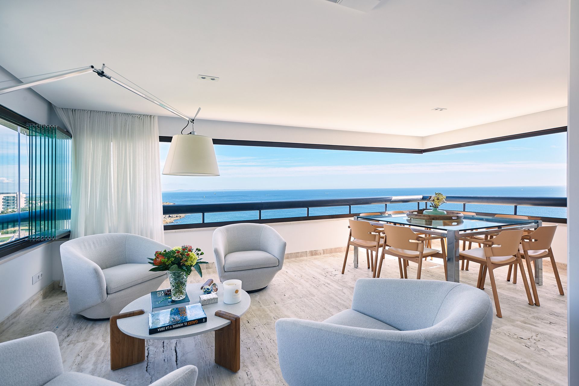 A living room with a table and chairs and a view of the ocean