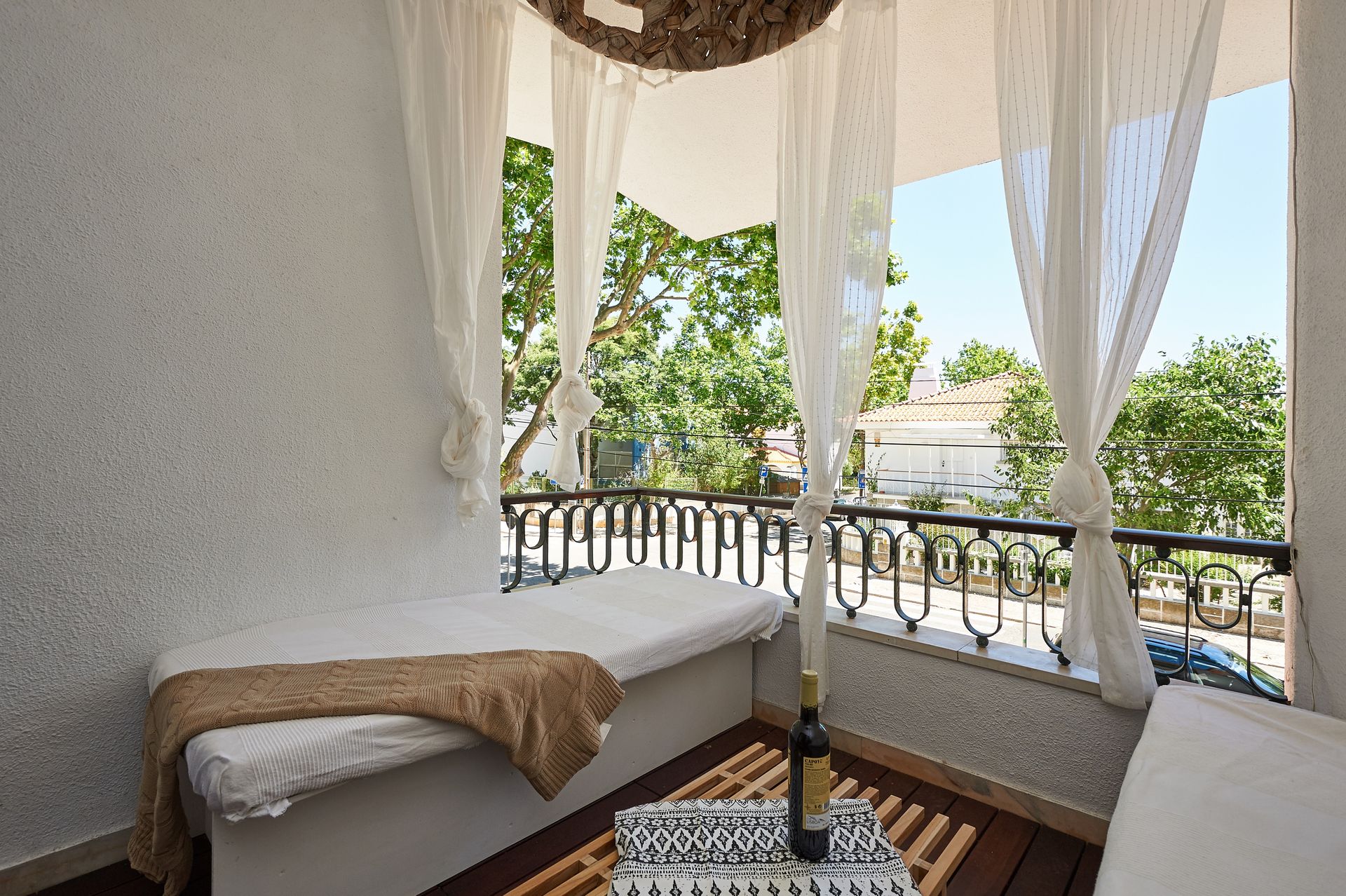 A balcony with a bed and a bottle of wine