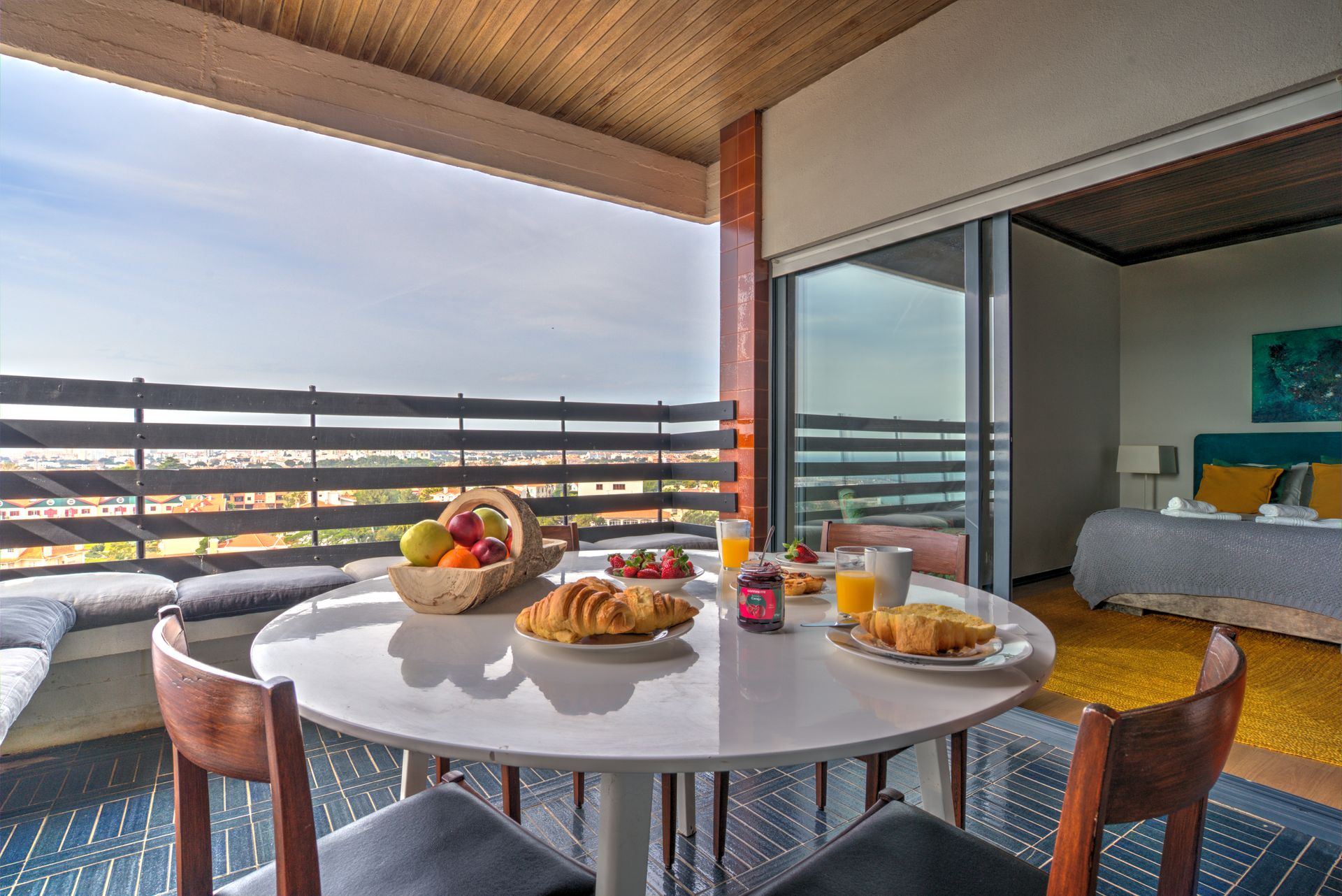 A table with plates of food on it in a room with a balcony.