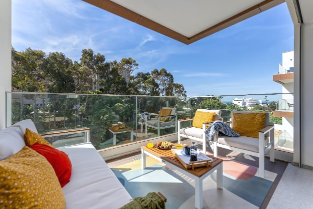 A balcony with a table and chairs and a view of the ocean.