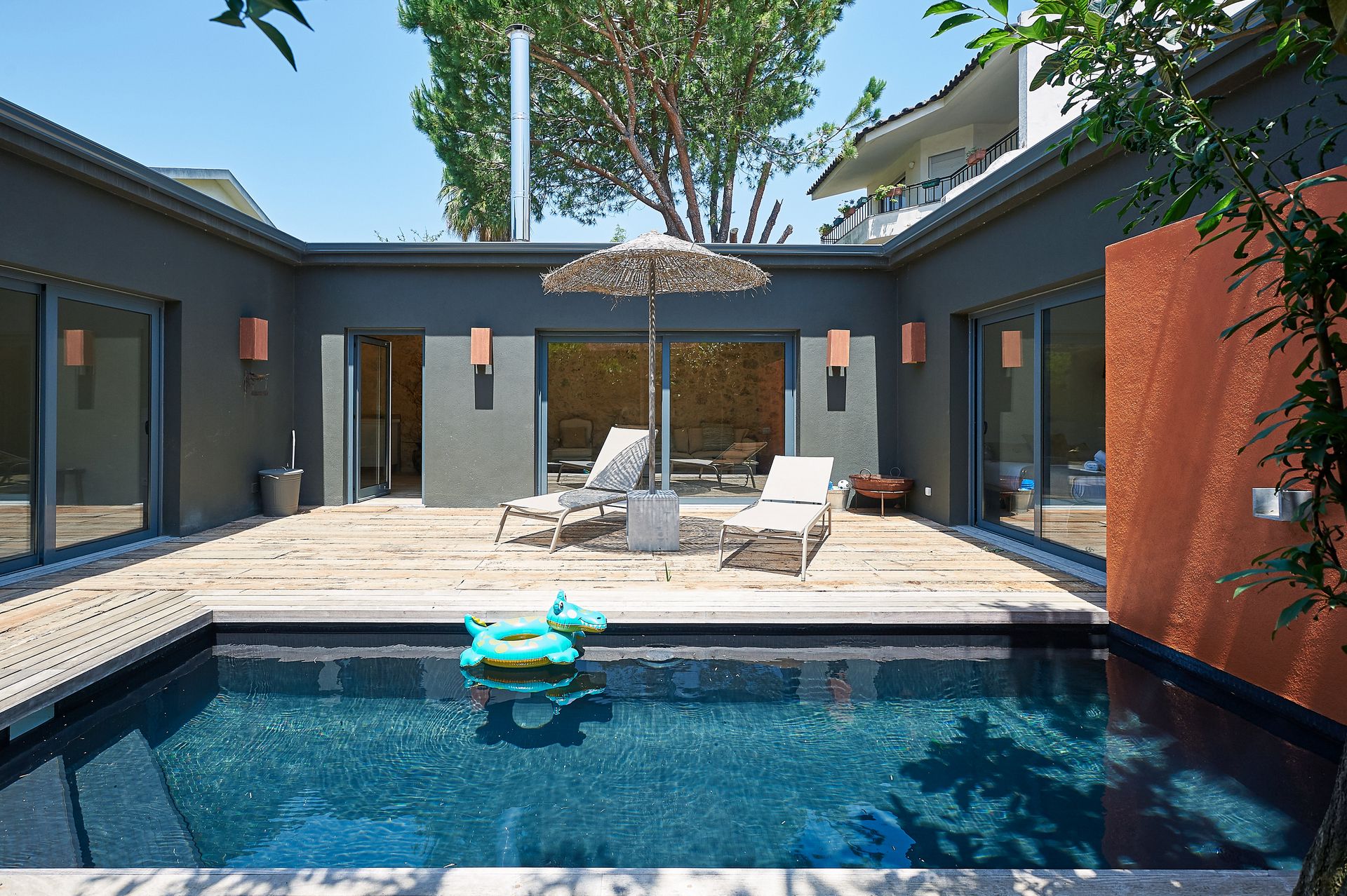 A swimming pool with an umbrella and chairs around it