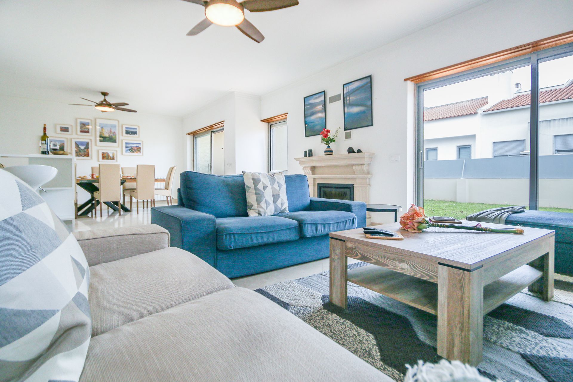 A living room with a blue couch , a coffee table , and a ceiling fan.