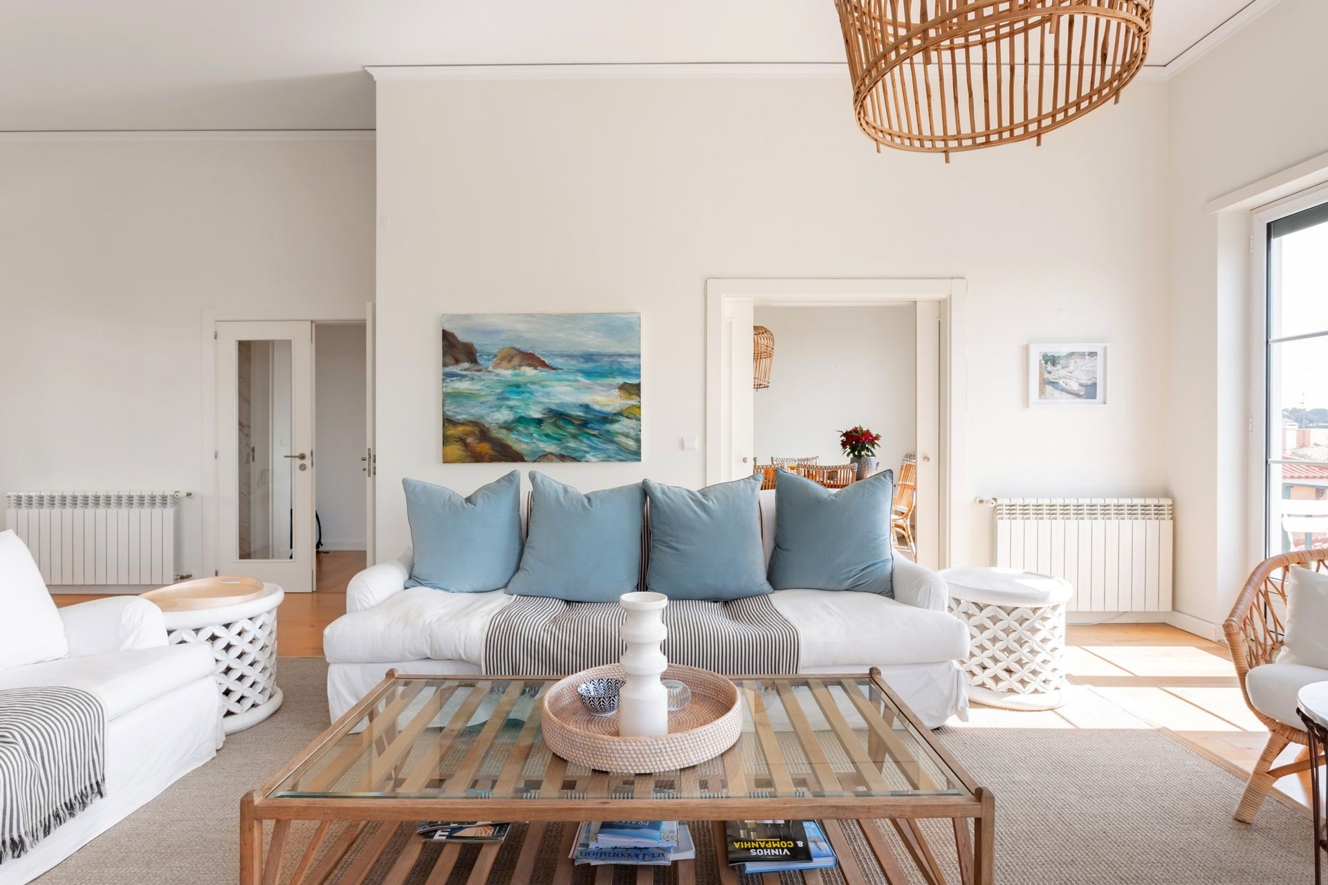 A living room with a couch , table , chairs and a painting on the wall.
