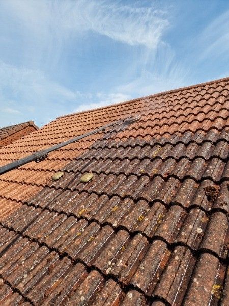 Weathered red tile roof under a blue sky with wispy clouds
